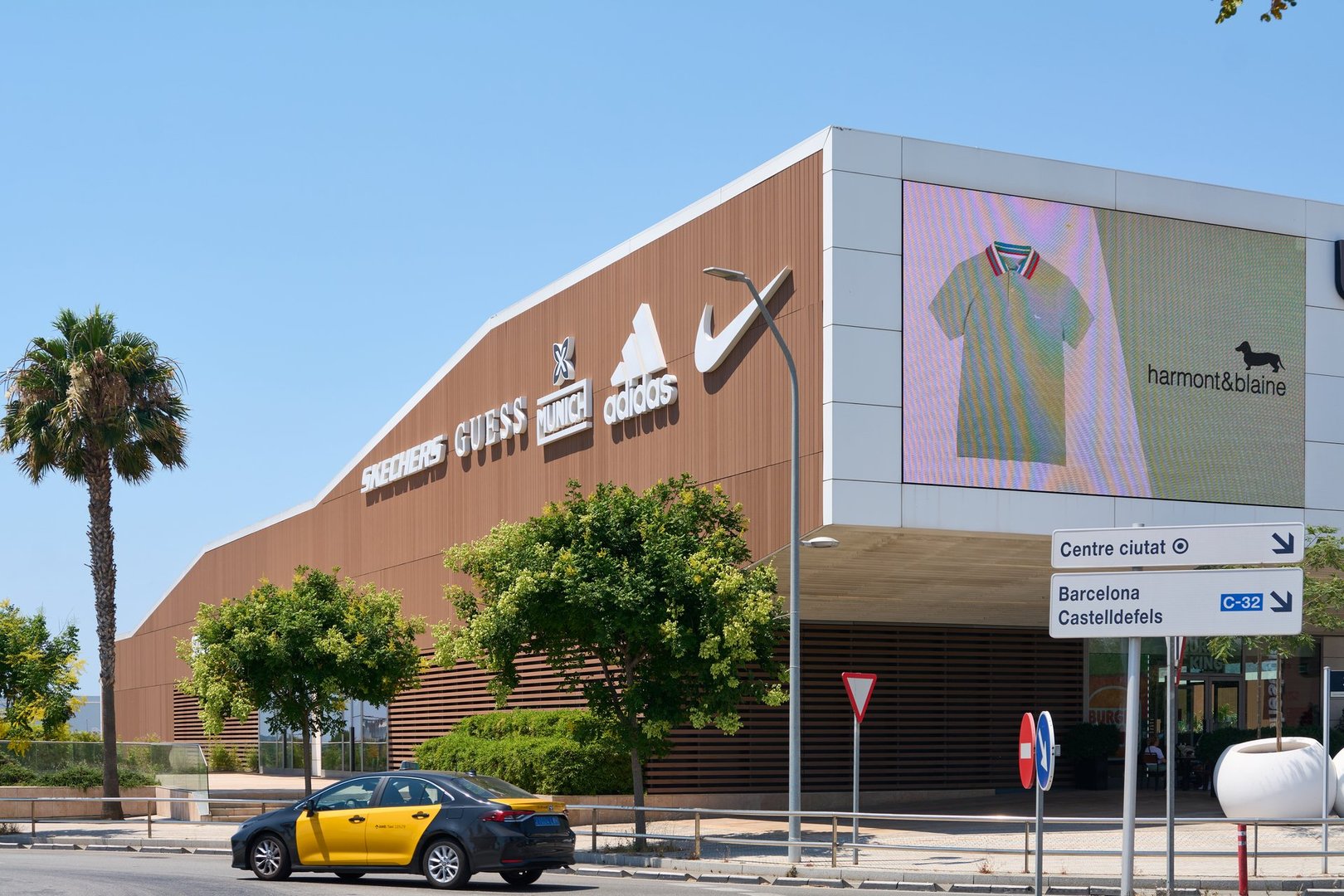Viladecans. Barcelona - August 29, 2025: Logos of Nike, Adidas, Guess, and Skechers stand out on the wooden facade of the Viladecans The Style Outlets center.