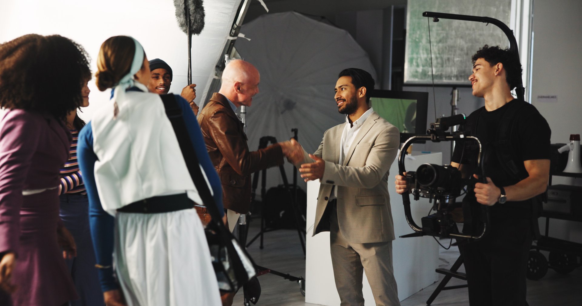 Handshake, teamwork and director in studio for creative production, filmmaking and shooting success. Behind the scenes, tech and cast with crew celebrate for videography, process and thank you on set