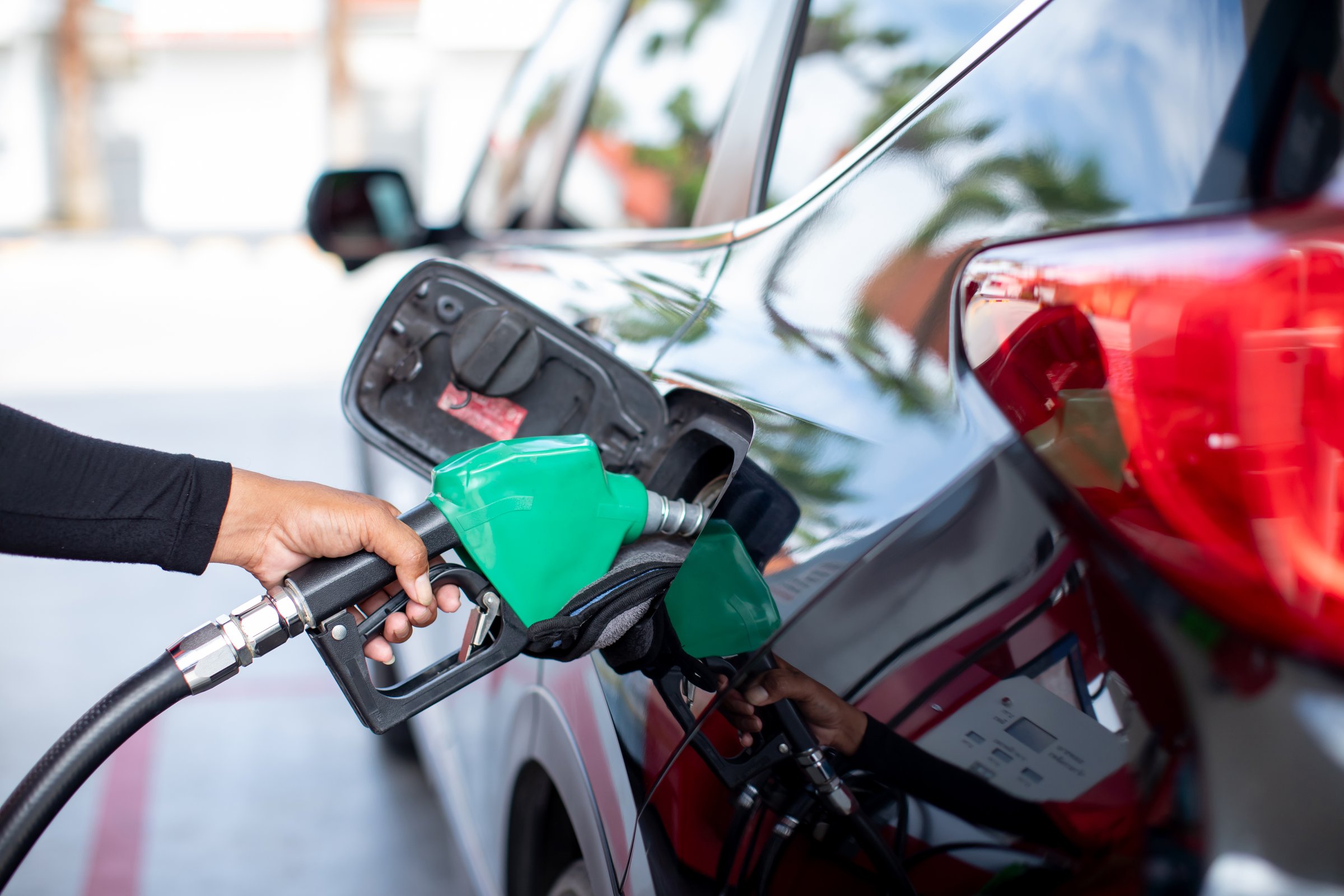 Selective focus to fuel nozzle with hand refilling the car at the gas  station, car in gas station, refilling the car with fuel at the refuel station, the concept of fuel energy.