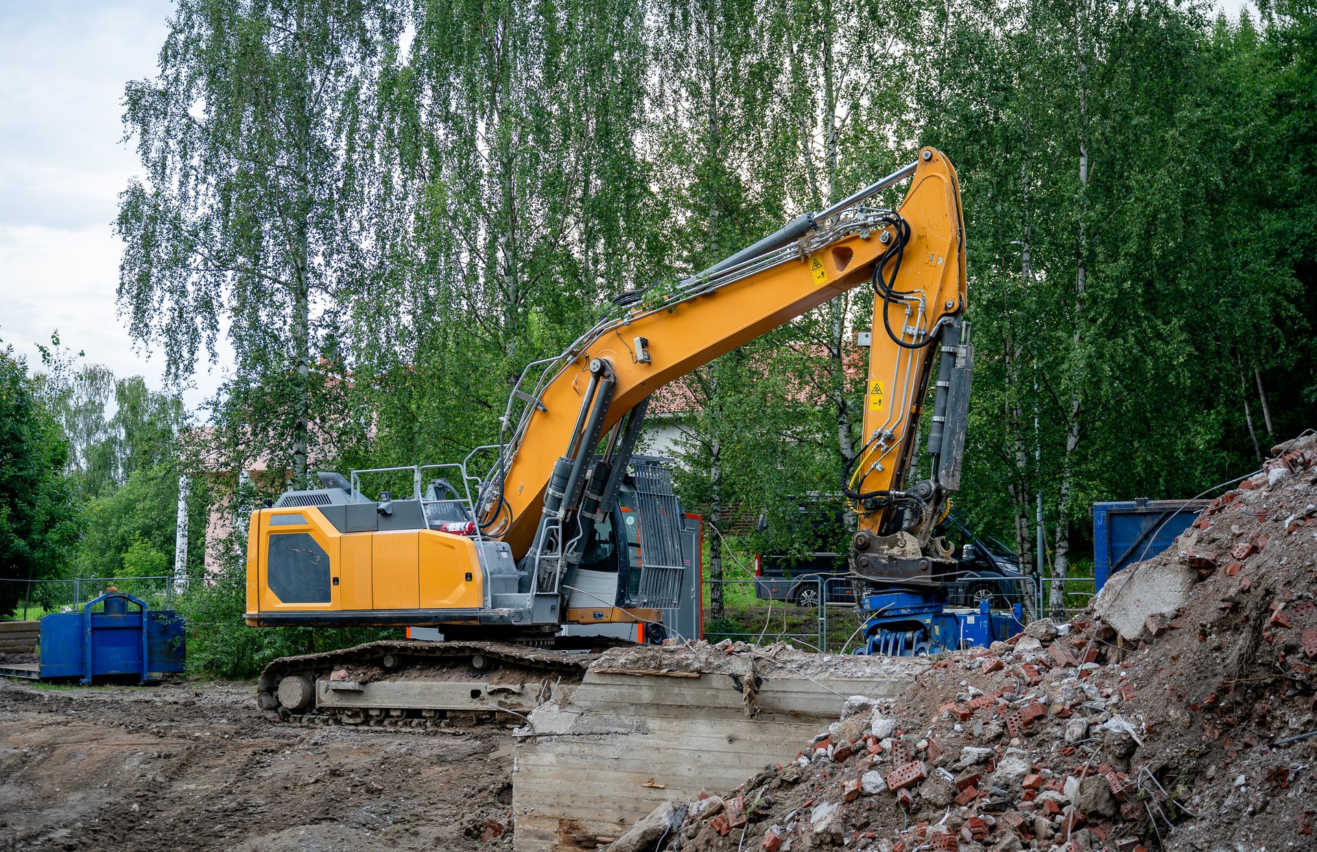 Yellow construction excavator tearing down old concrete