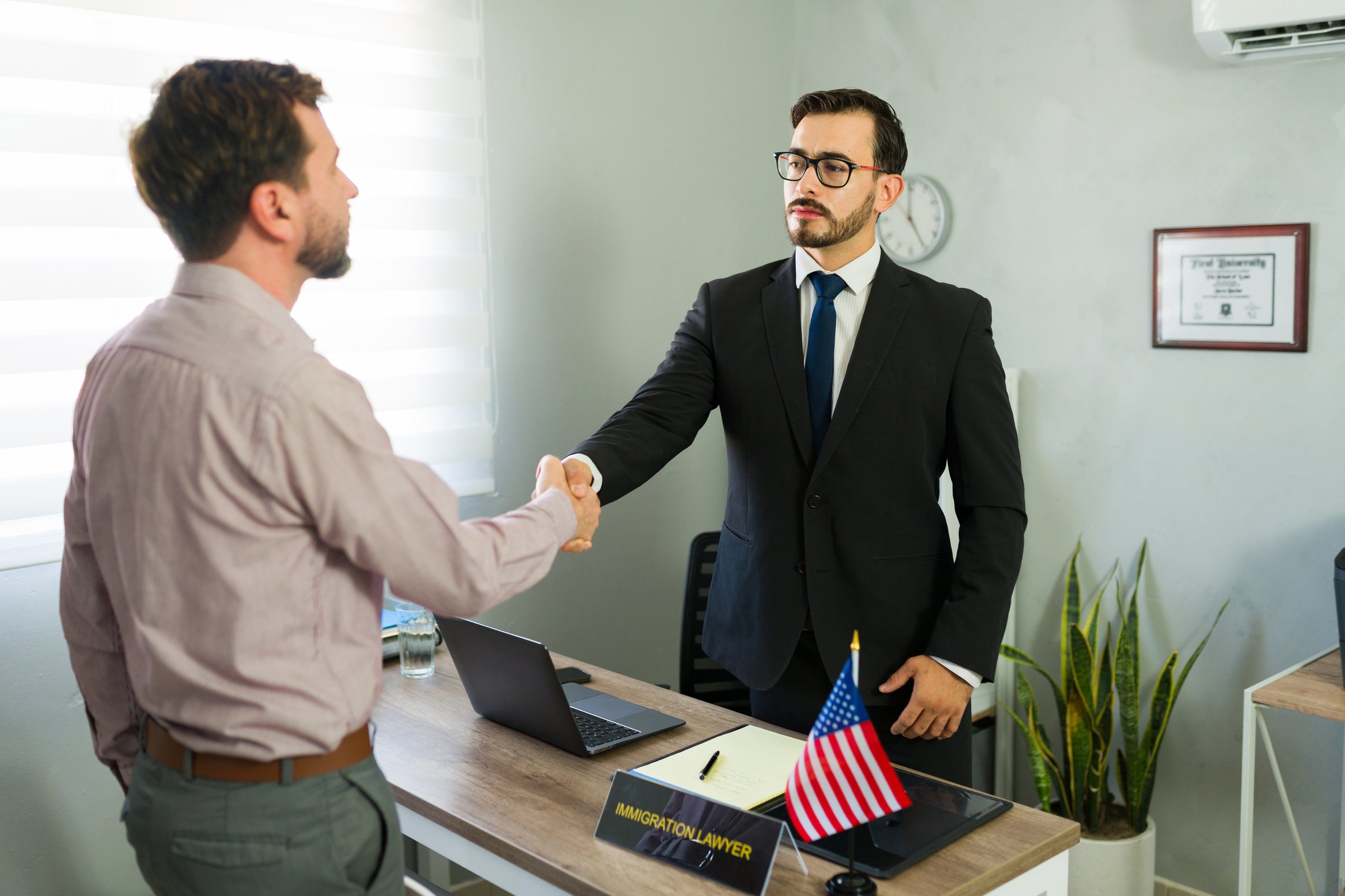 Man client and male immigration lawyer shaking hands, making an agreement during a legal consultation in the office