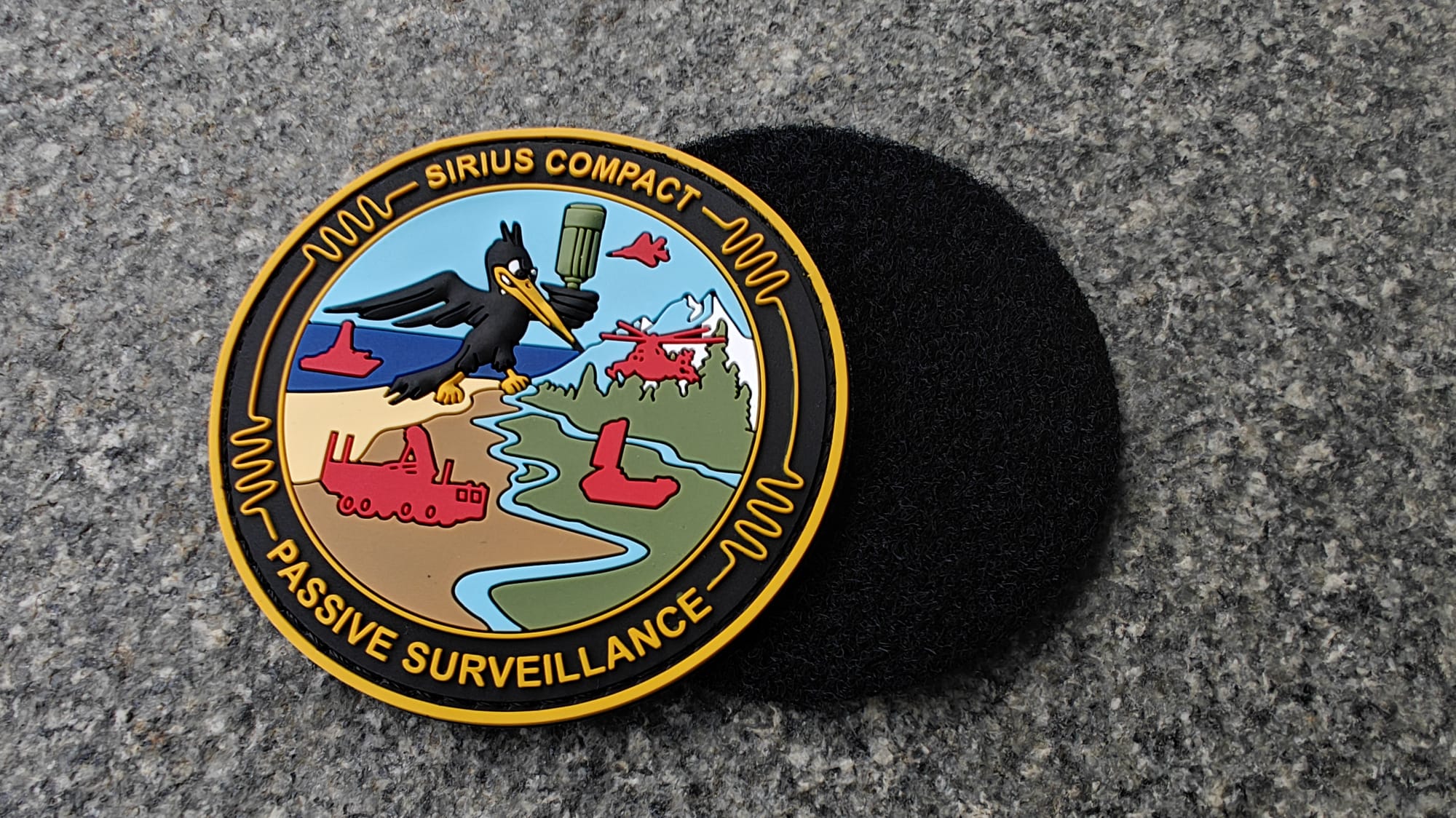 Circular patch with a bird, military vehicles, and text Sirius Compact Passive Surveillance on a textured background.