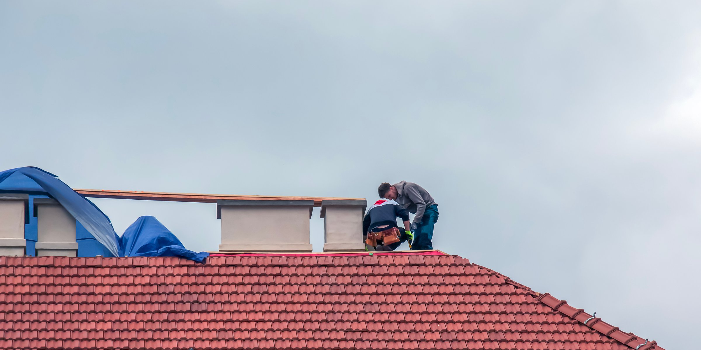 Nitra, Slovakia - 05.15.2023: Handymen repair chimneys on the roof of a house.