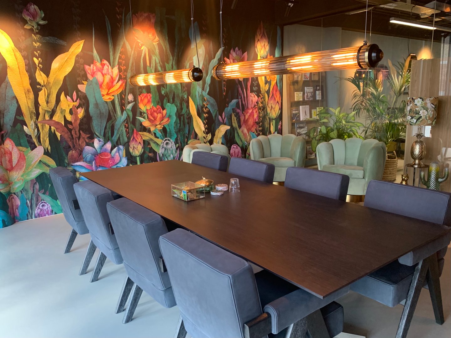 Modern dining room with a wooden table, gray chairs, colorful floral wall mural, and elegant lighting fixtures.