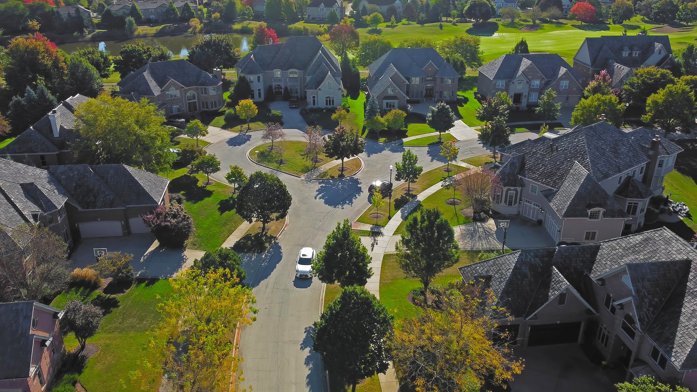 Aerial View of Luxury Suburban Neighborhood in Chicago. High-angle aerial view of an upscale suburban neighborhood in Chicago, Illinois, featuring large homes, green lawns, and a circular street