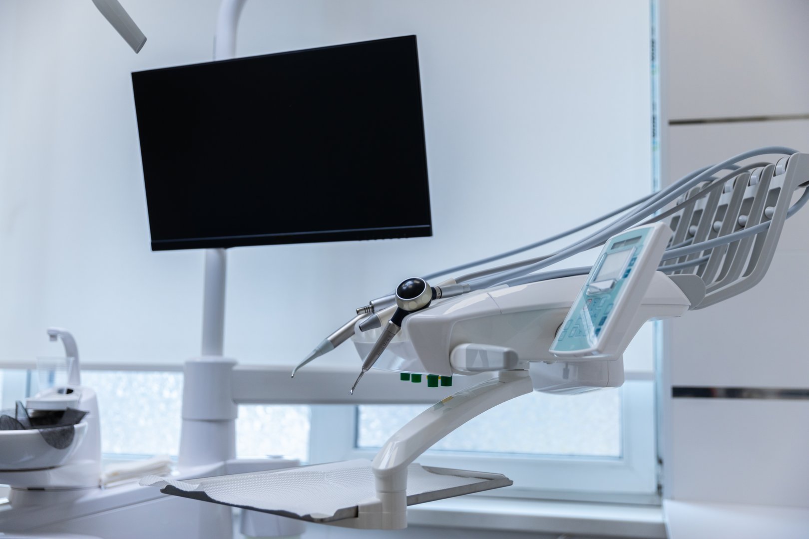 A sleek dental setup featuring a modern chair, tools, and a large monitor, providing a professional atmosphere for dental procedures in an inviting clinic environment.