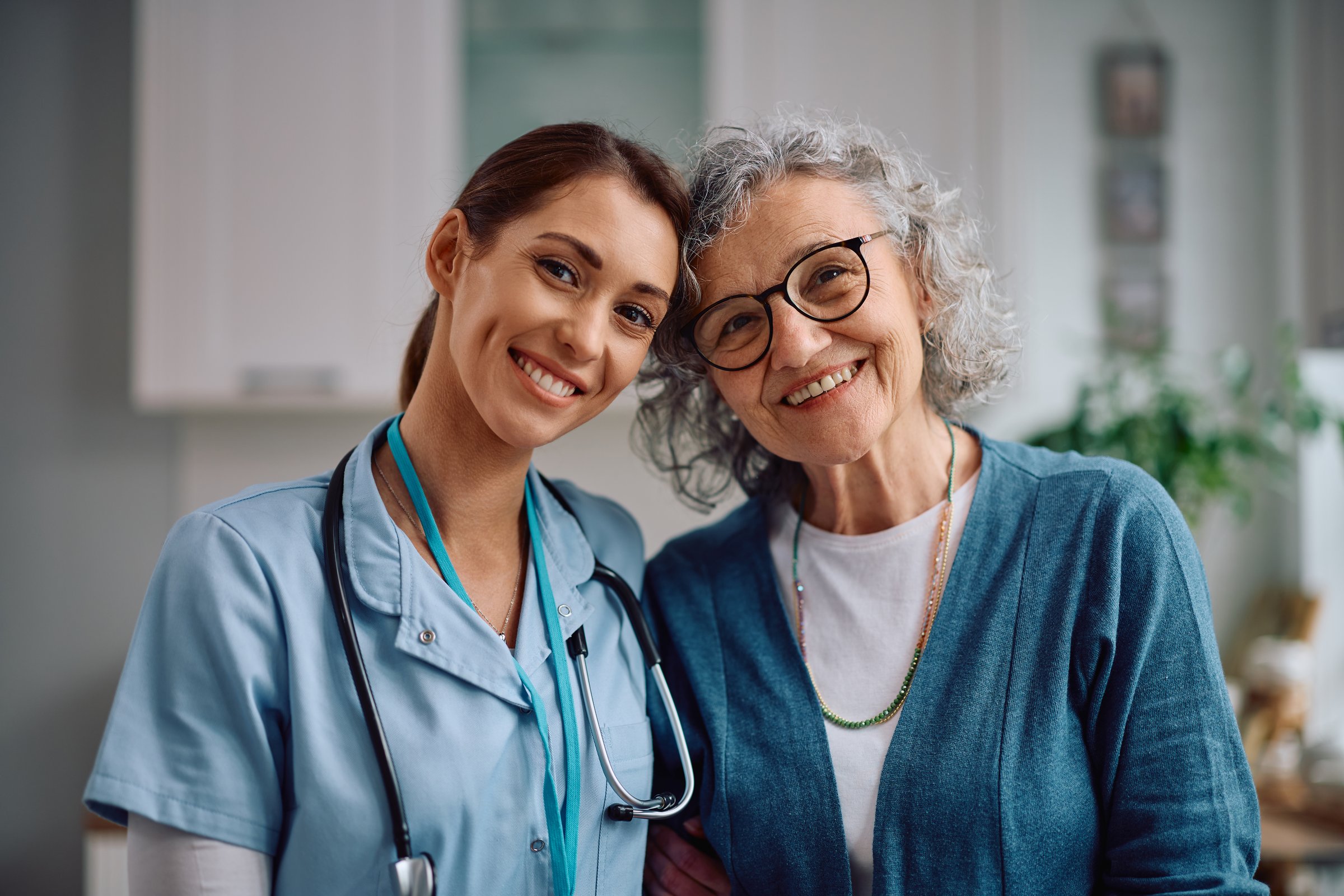 Happy doctor with female  senior patient during her home visit looking at camera.
