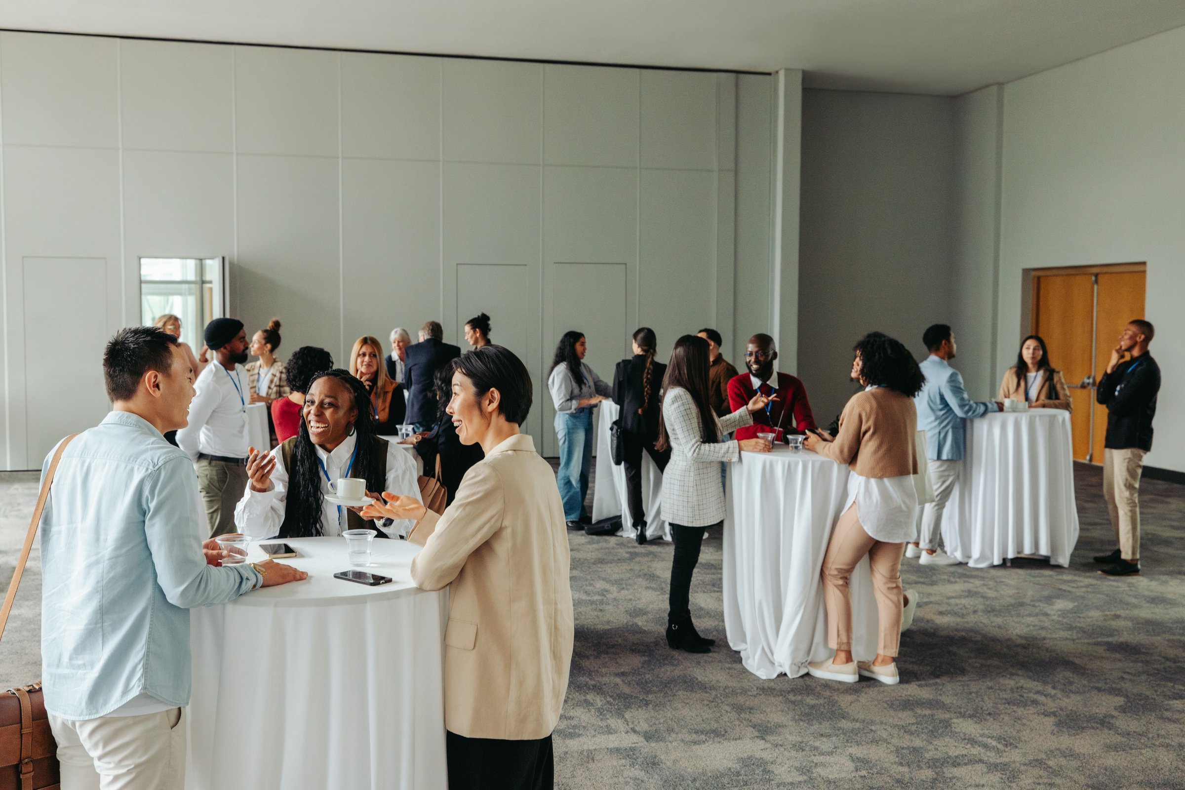 Group of diverse professionals networking and socializing during a business conference. People engaged in conversations and enjoying refreshments.