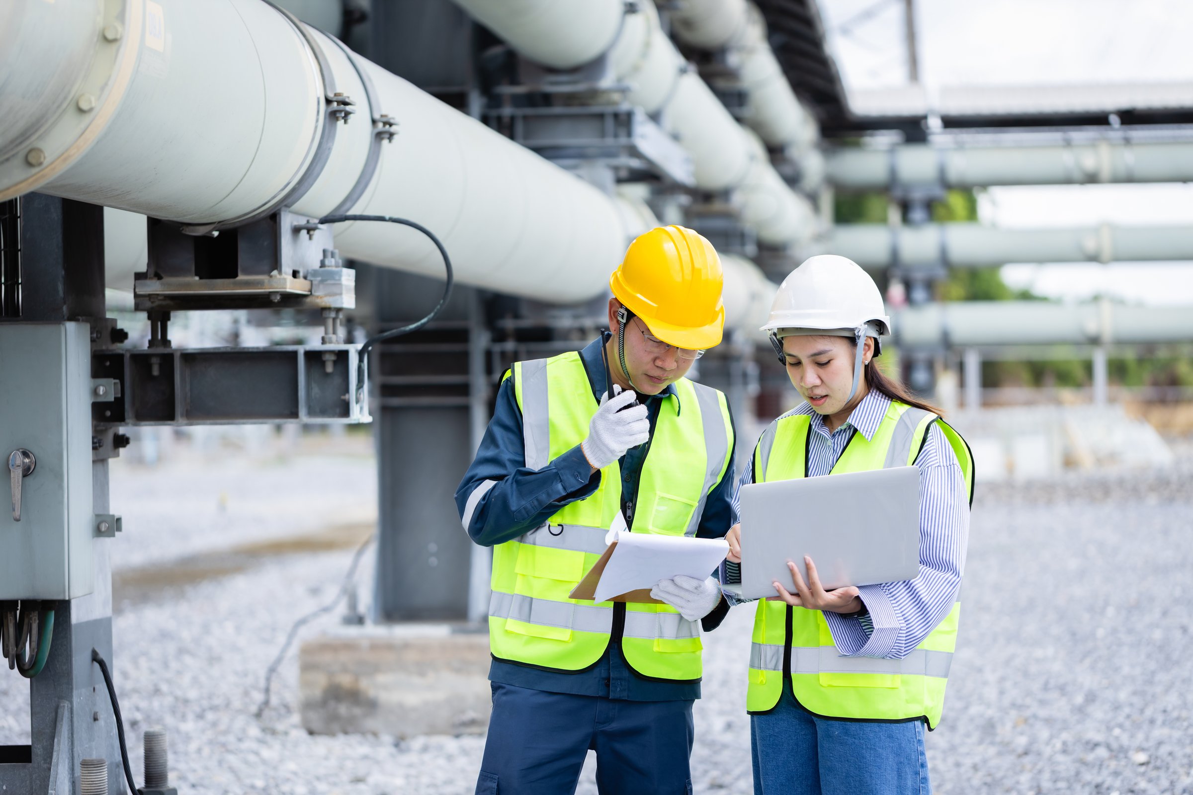 An engineer working at power substation high voltage infrastructure inspection and check with safety helmet and vest in industrial environment