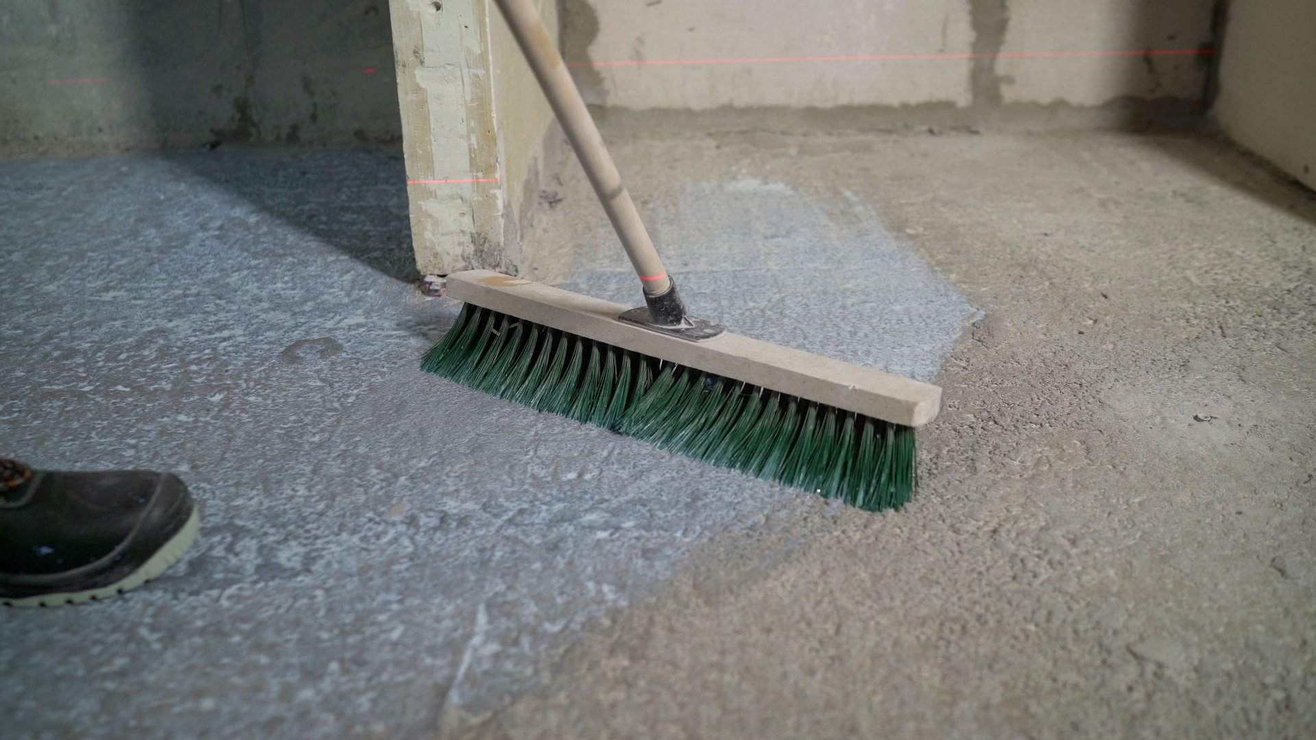 The process of priming concrete floors. With a special brush, level the primer on the floor