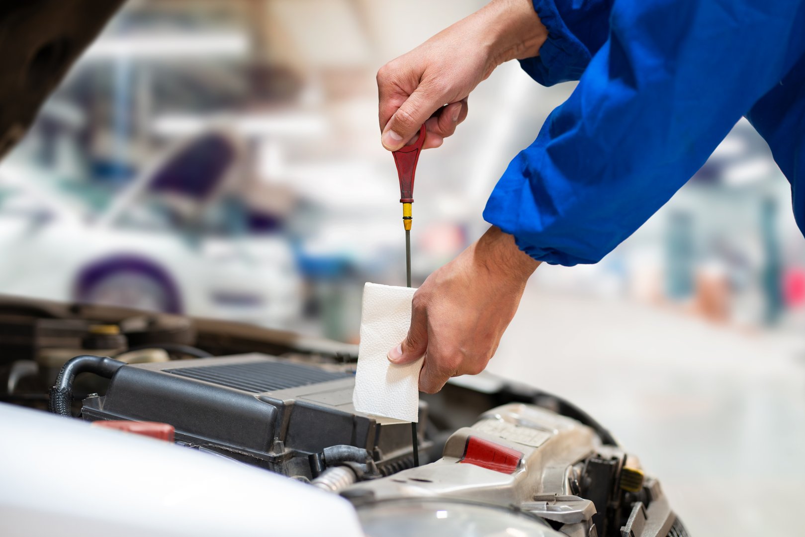 Close up of a car mechanic checking oil level in a mechanical at workshop