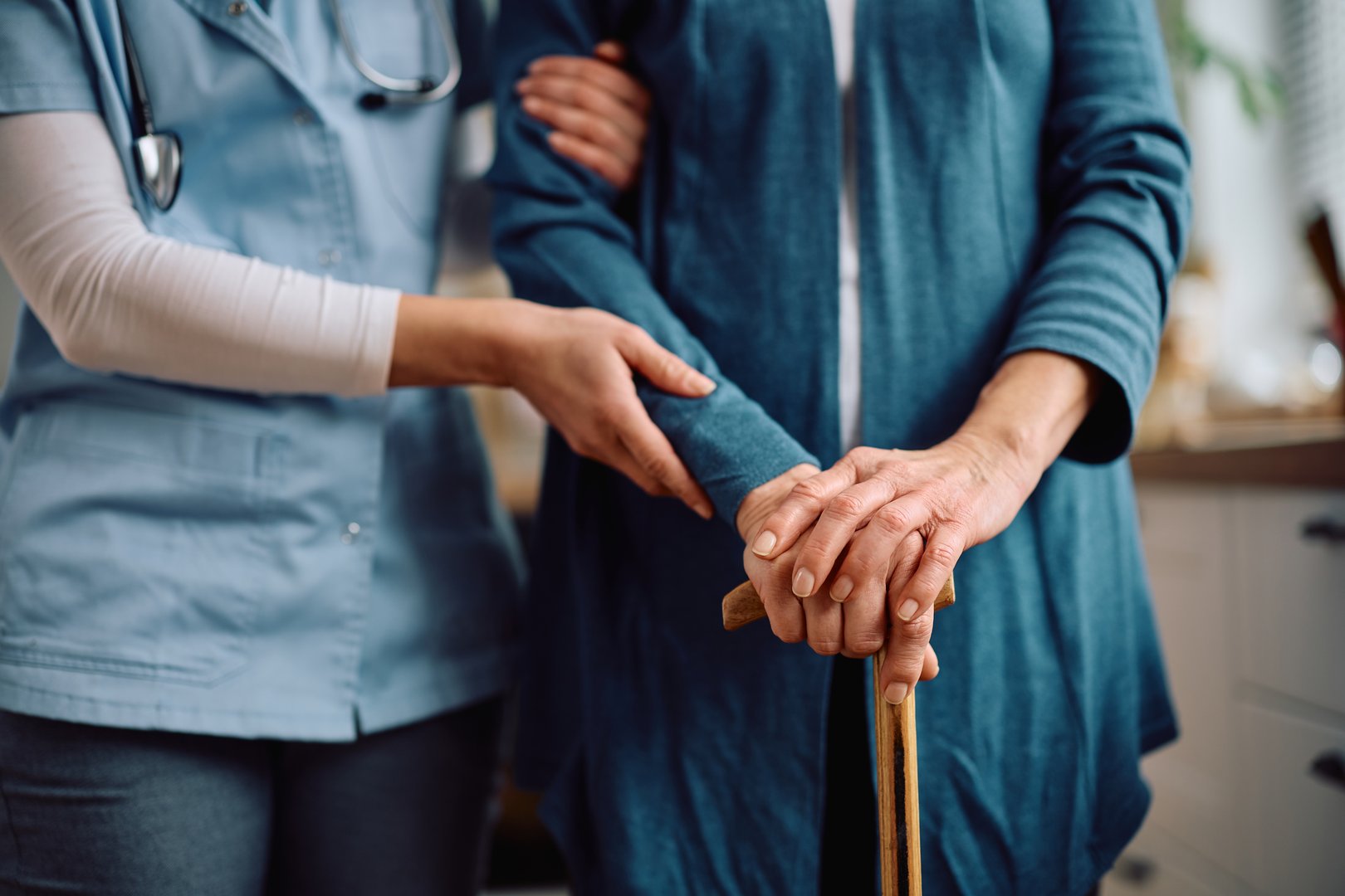 Close up of elderly woman with walking cane and visiting nurse at home.