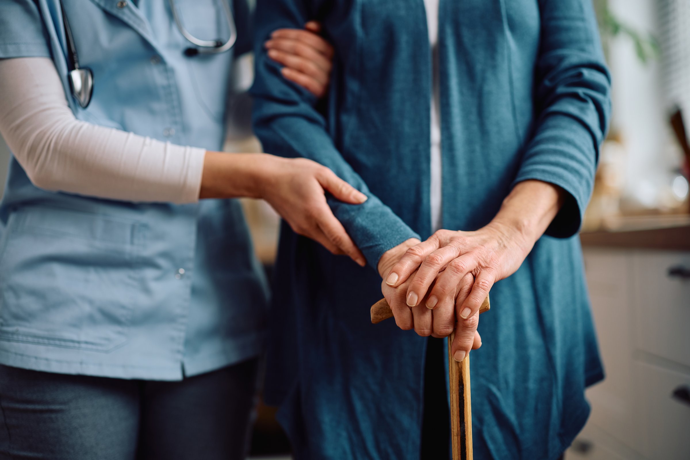 Elderly woman with walking cane and visiting nurse
