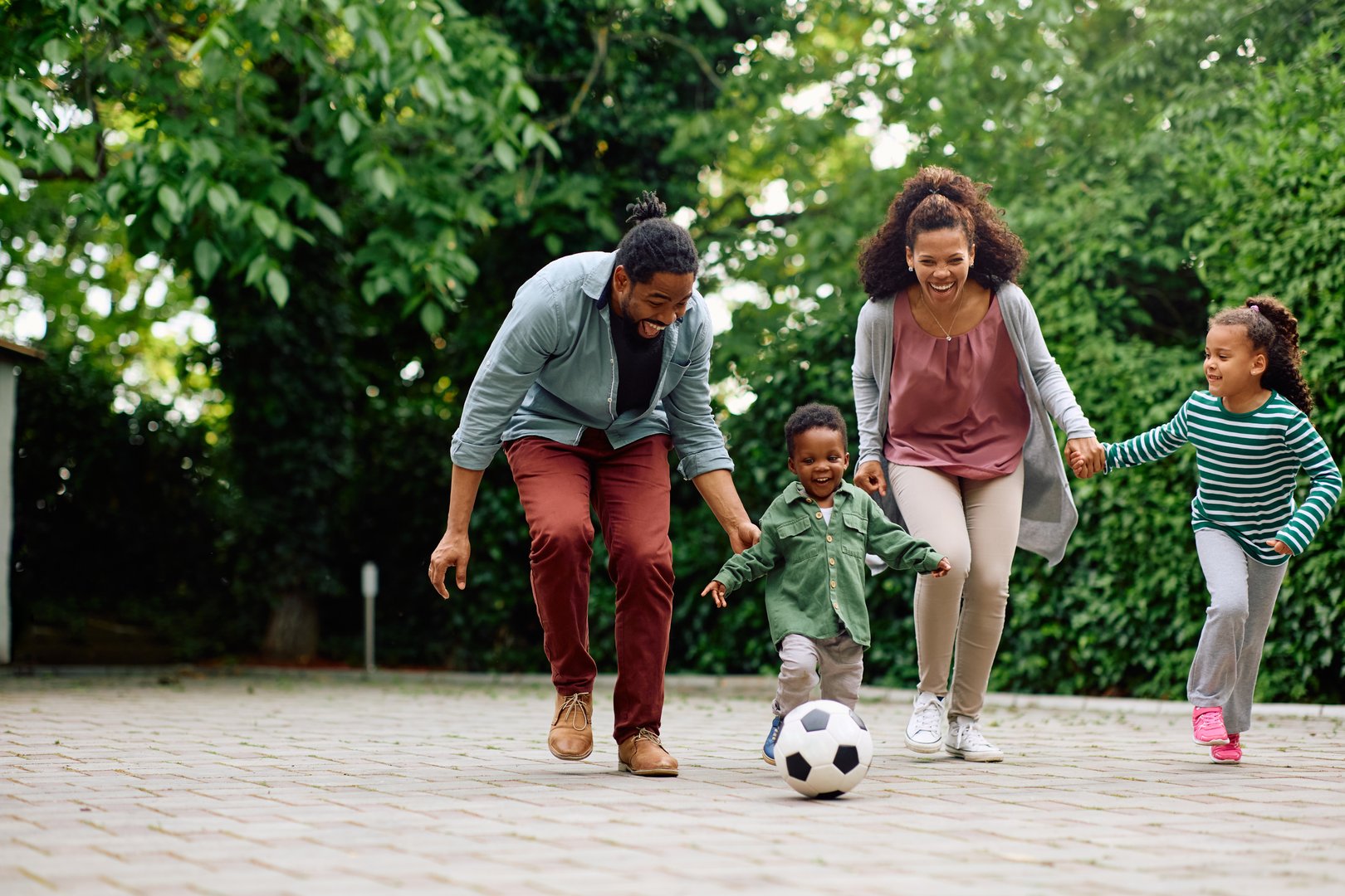 Familia afroamericana jugando fútbol en jardín - diversión familiar