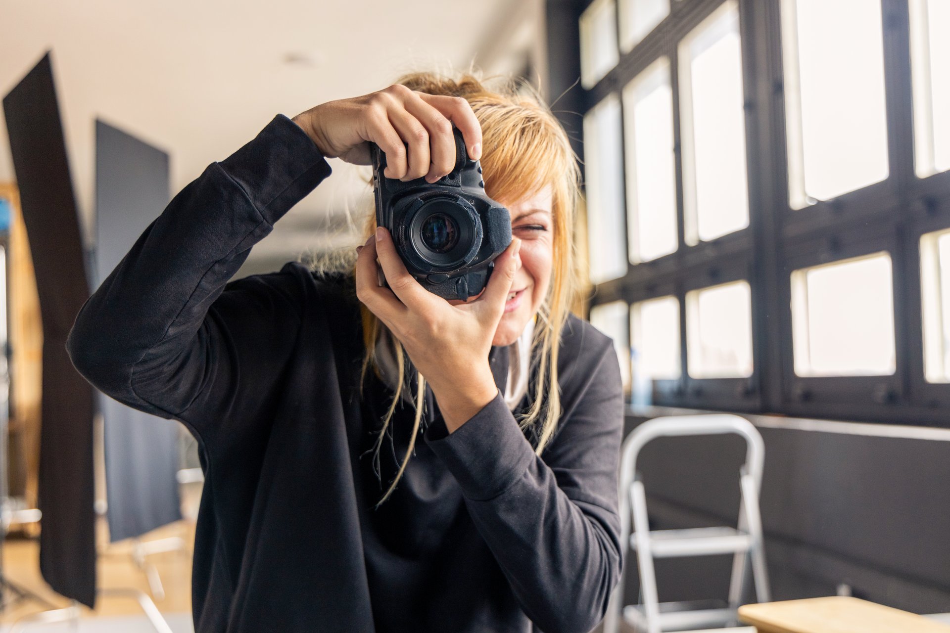 Photographer smiling and taking pictures with professional camera in a studio