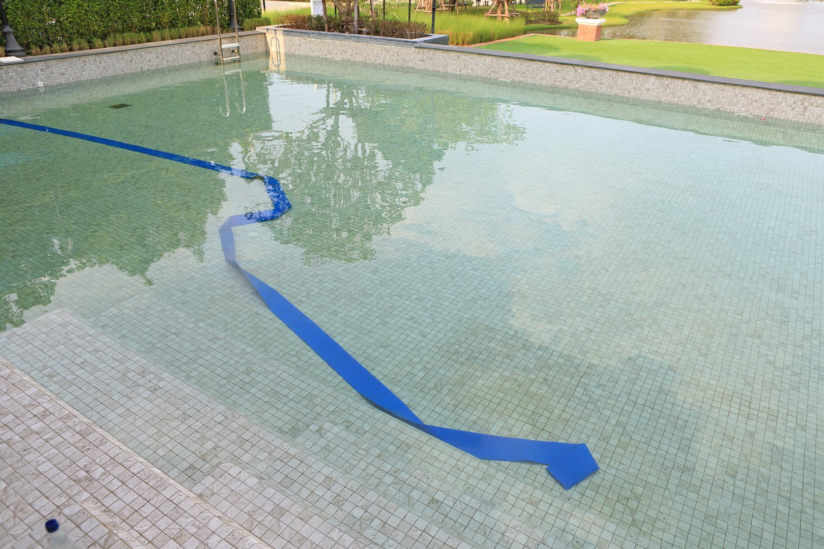 Pool is under maintenance with blue rubber hoses immersed. Change new water.