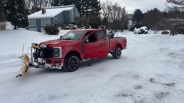 Professional snow plowing service with plow truck in action