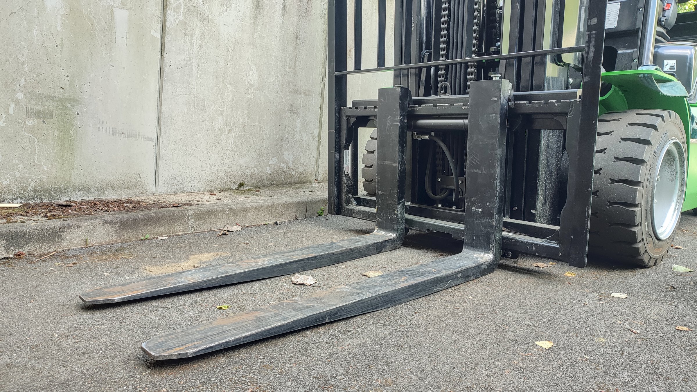 Forklift forks and front wheels near concrete wall