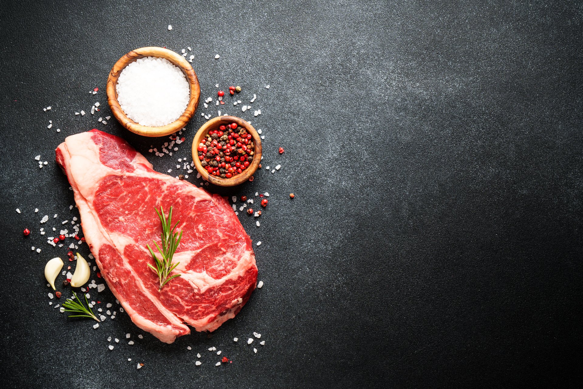 Beef steak. Ribeye steak raw meat on black. Top view with copy space.