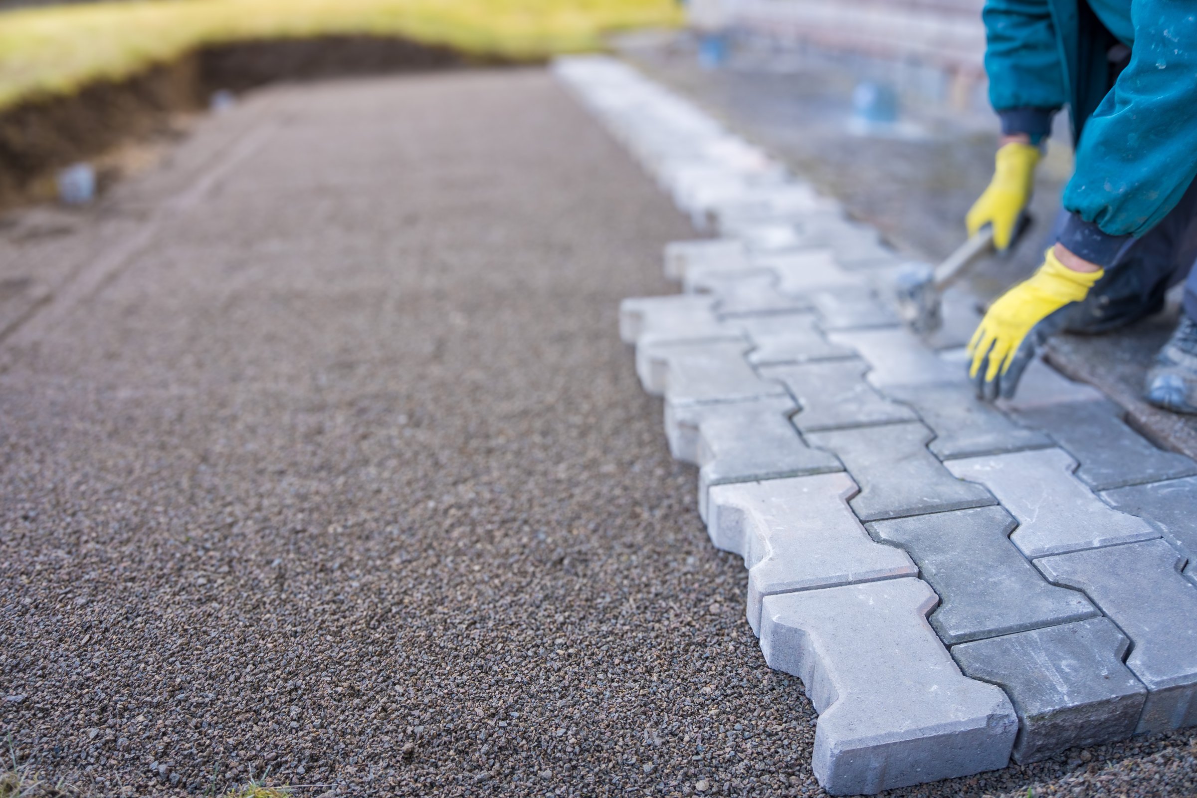 Laying gray concrete paving slabs in house courtyard driveway patio