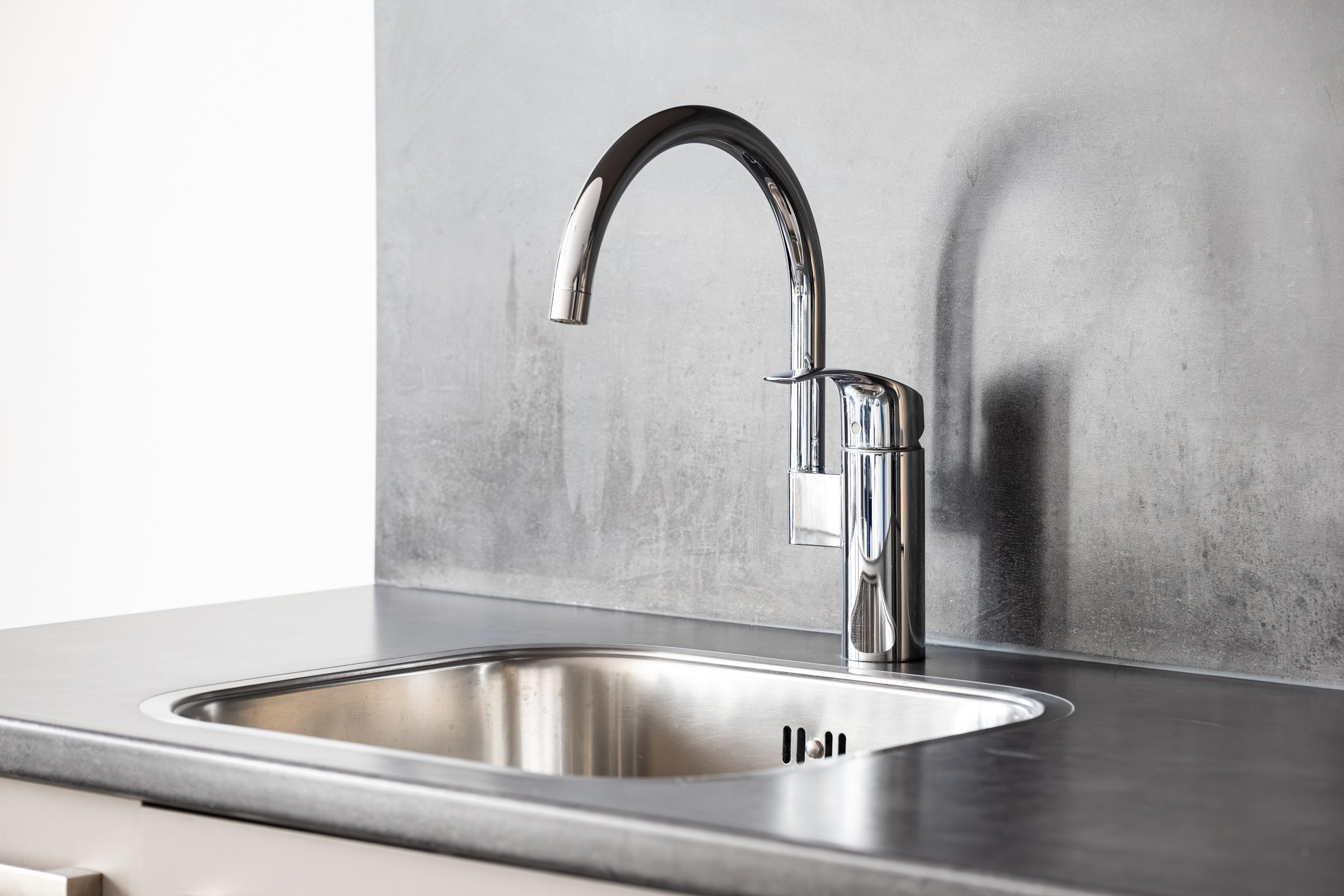 Closed, new, stainless water tap faucet and sink in apartment kitchen. Bright, natural window light, selective focus, no people