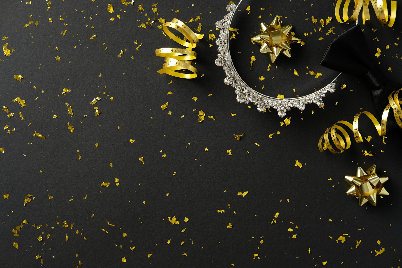 Prom celebration, high school graduation party concept. Top view diadem and sparkle party decorations on black background