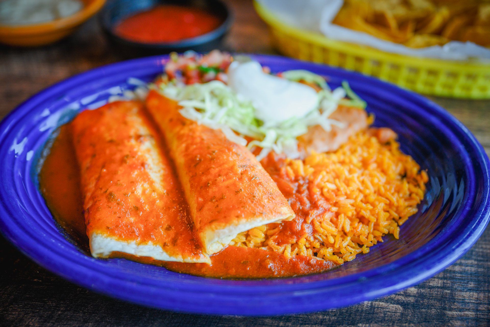 Chicken and beef burritos Home-style served on blue plate on the wooden table, traditional Mexican dinner with rice and bean
