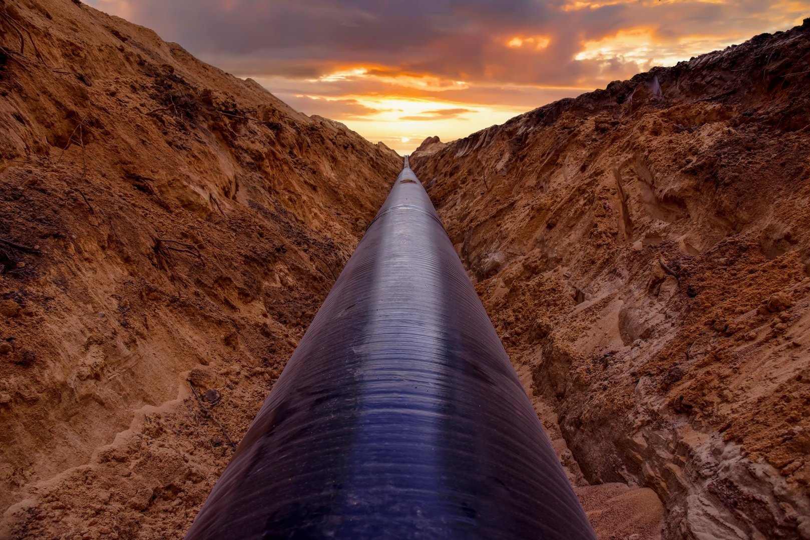 Pipeline Construction. Natural Gas Pipeline trench in ground on sunset.  LNG, LPG. Oil and Gas Transportation crude oil, natural gas. Crude pipeline. Pipework. Pipes for Petrochemical industry.