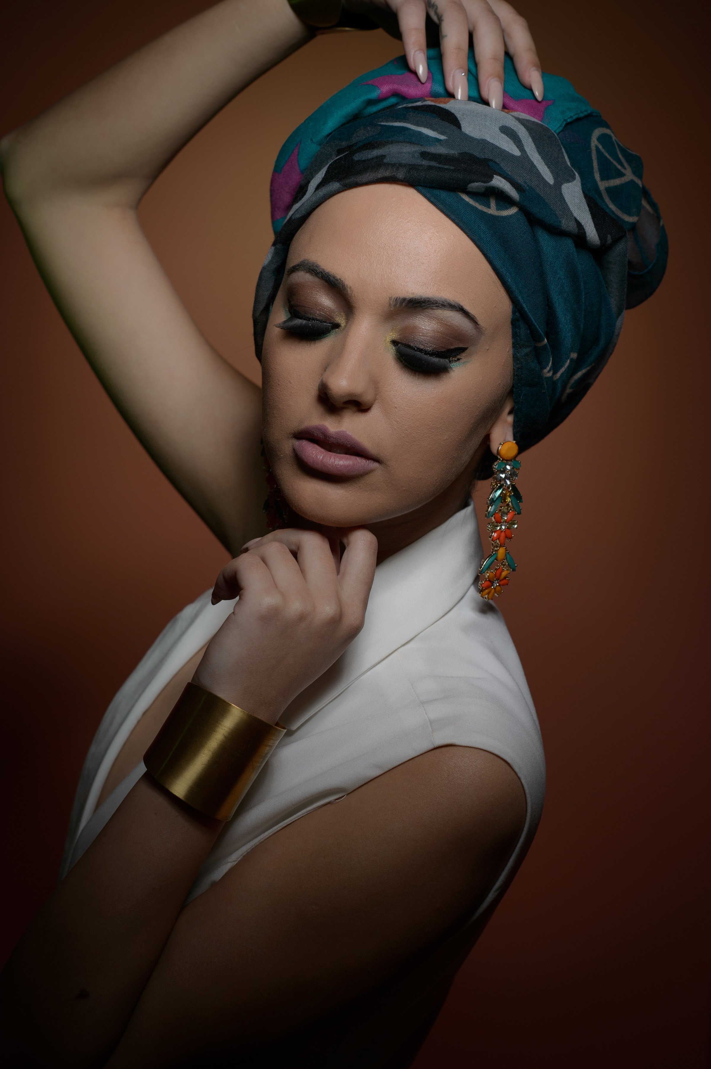 Beautiful woman in a turban.Young beautiful woman with turban and golden accessories.Beauty fashionable woman with hairs wrapped in turban. Pretty Caucasian model wearing  earrings  posing in studio.