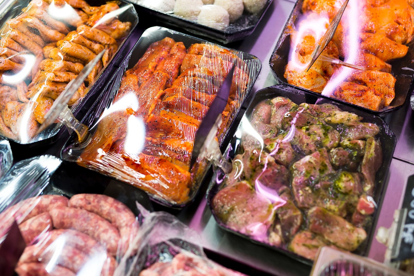 Meats in marinade on supermarket display, pre-cooked food
