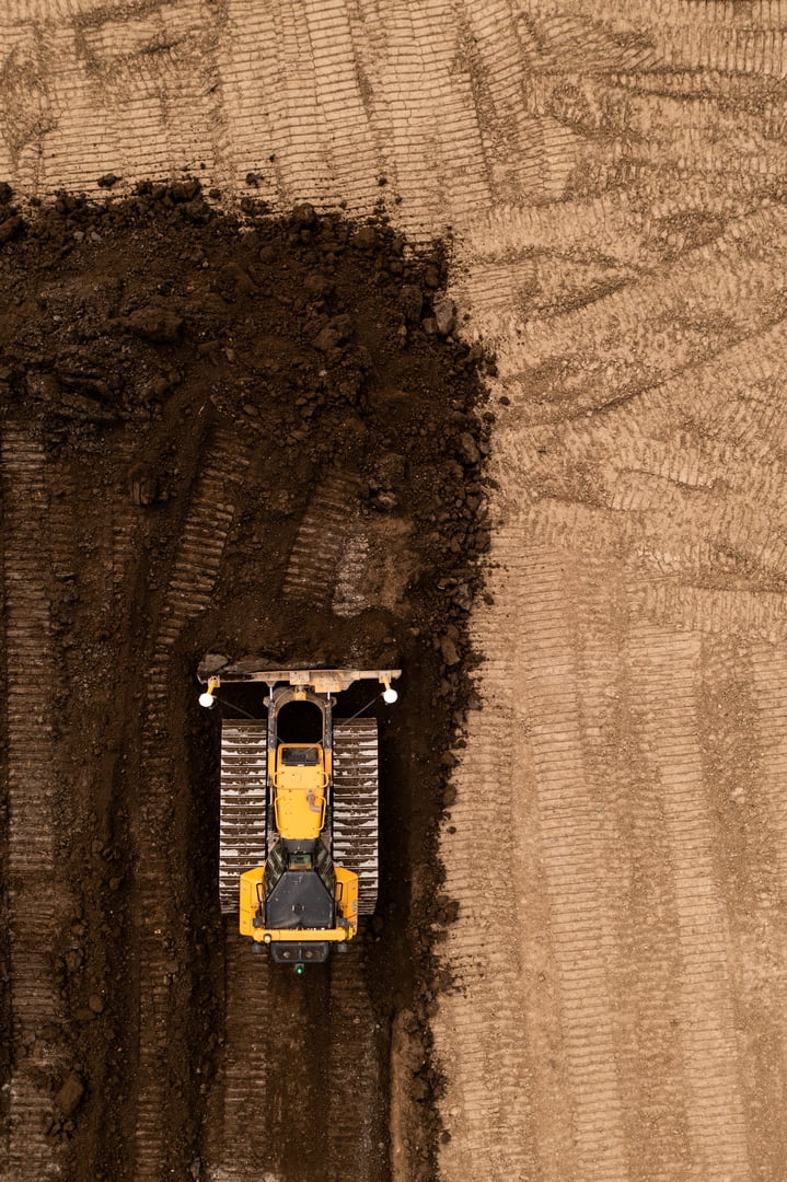 Aerial view directly above a bulldozer or earth moving machine with tracks pushing earth and soil in the construction industry on a brownfield site with copy space