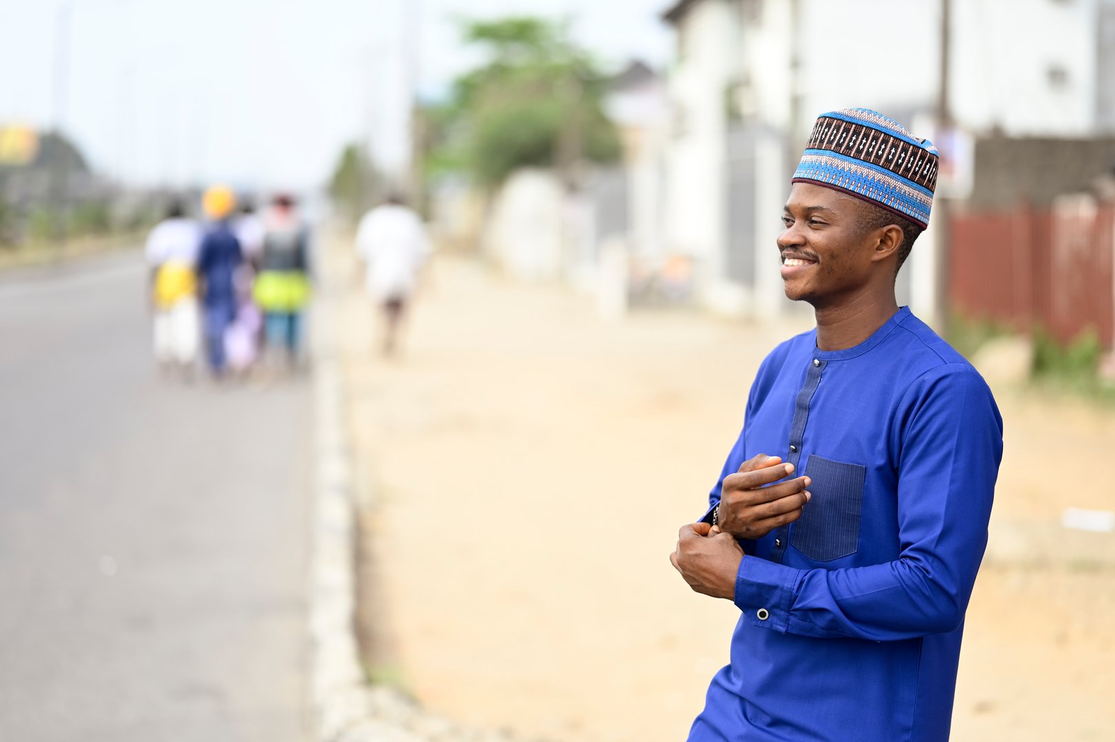 A traditional businessman from the African clan wearing blue attire and  Outdoor on a busy street, standing by the Roadside and copy space.