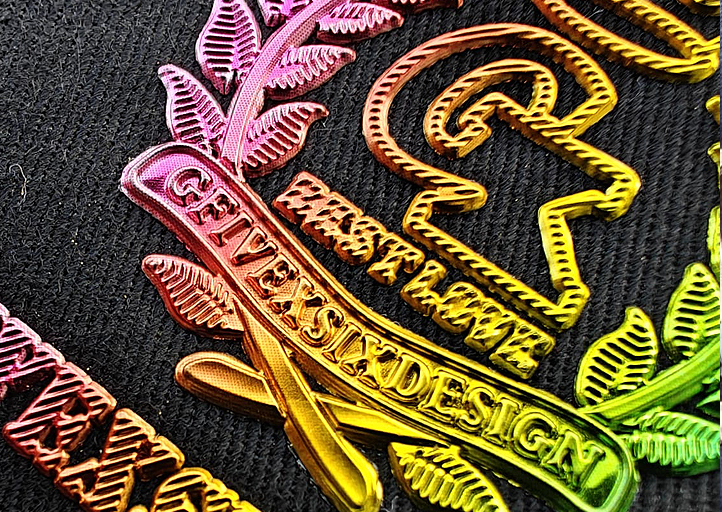 Close-up of a colorful embroidered GFV EX SIX DESIGN patch with leaf and text details on a dark fabric.