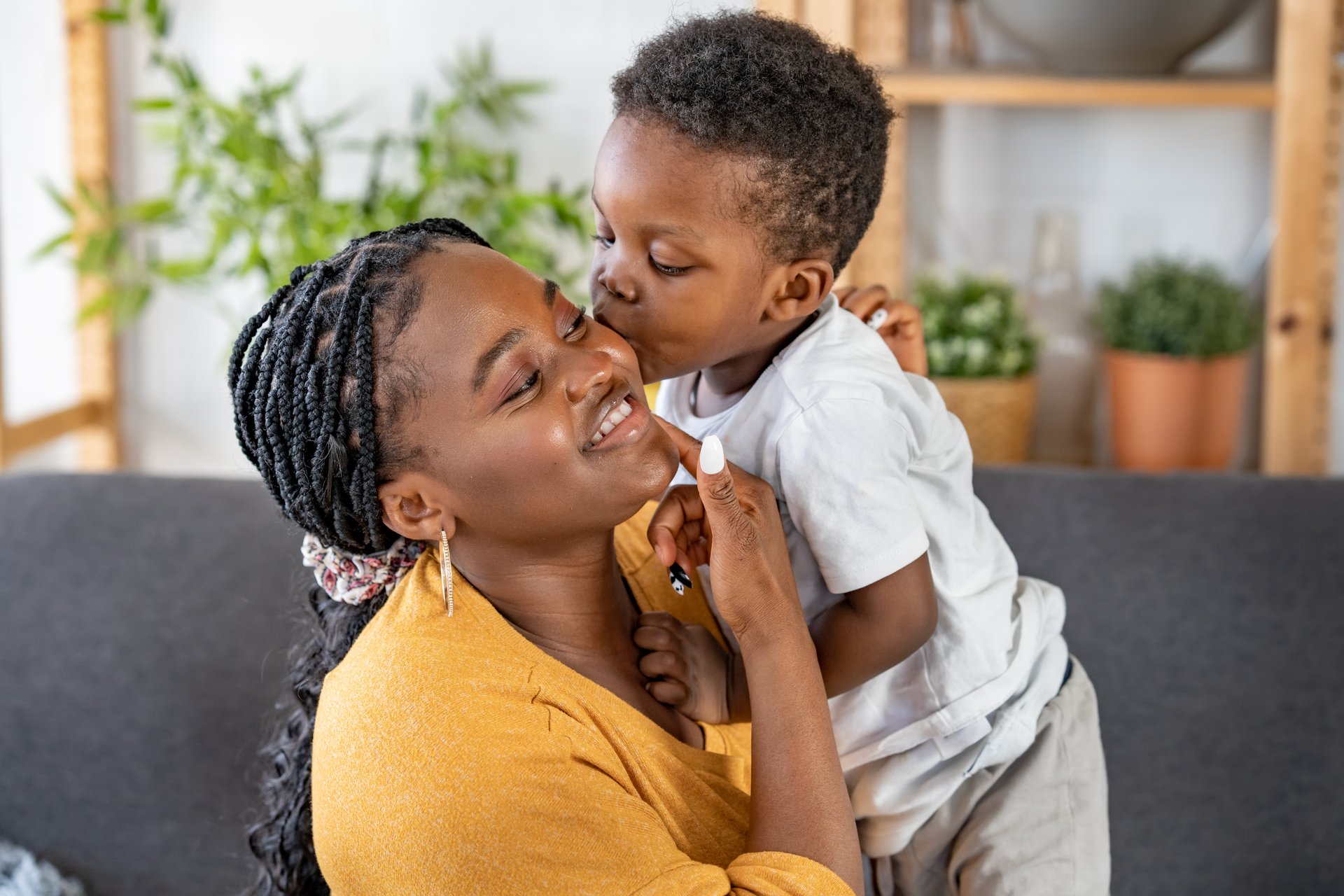 Cheerful African-American mother and son cuddling, laughing, and having fun at home. Family bonding time. Mothers day