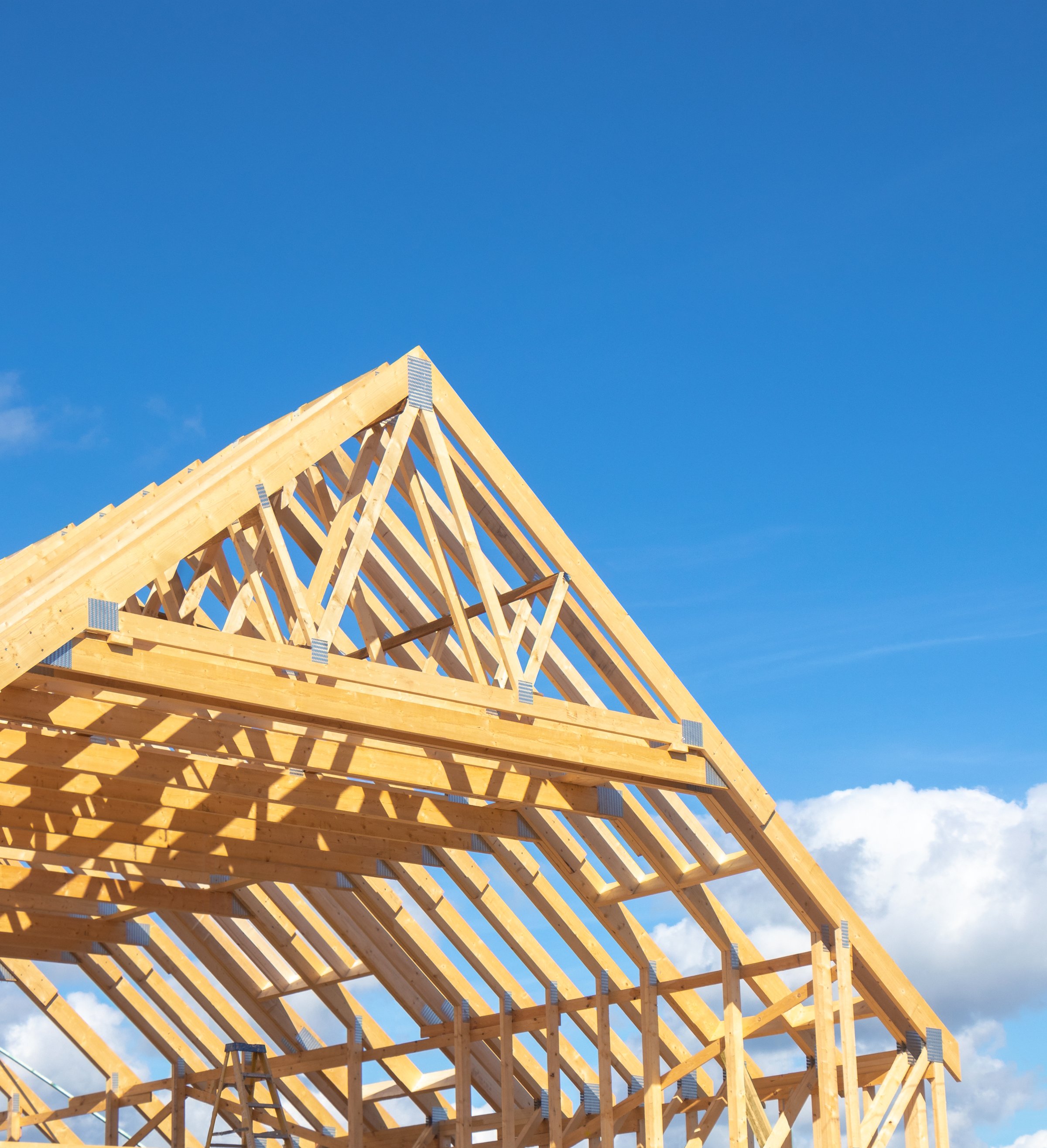Partly assembled roof frame using stubbed eaves trusses comprised of a series of sloped wooden, structural members. Similar to a timber rafter construction for attic space. Plenty of empty copy space.