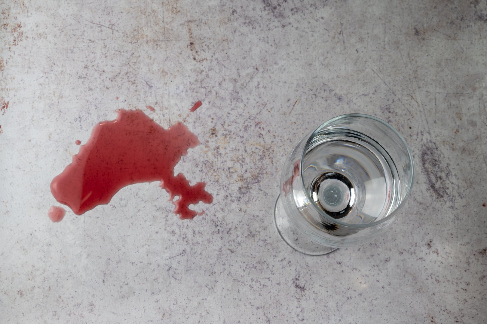 Top view of a glass filled with water next to a spilled red wine stain, symbolizing conscious choice, sobriety, moderation, and lifestyle decisions.
