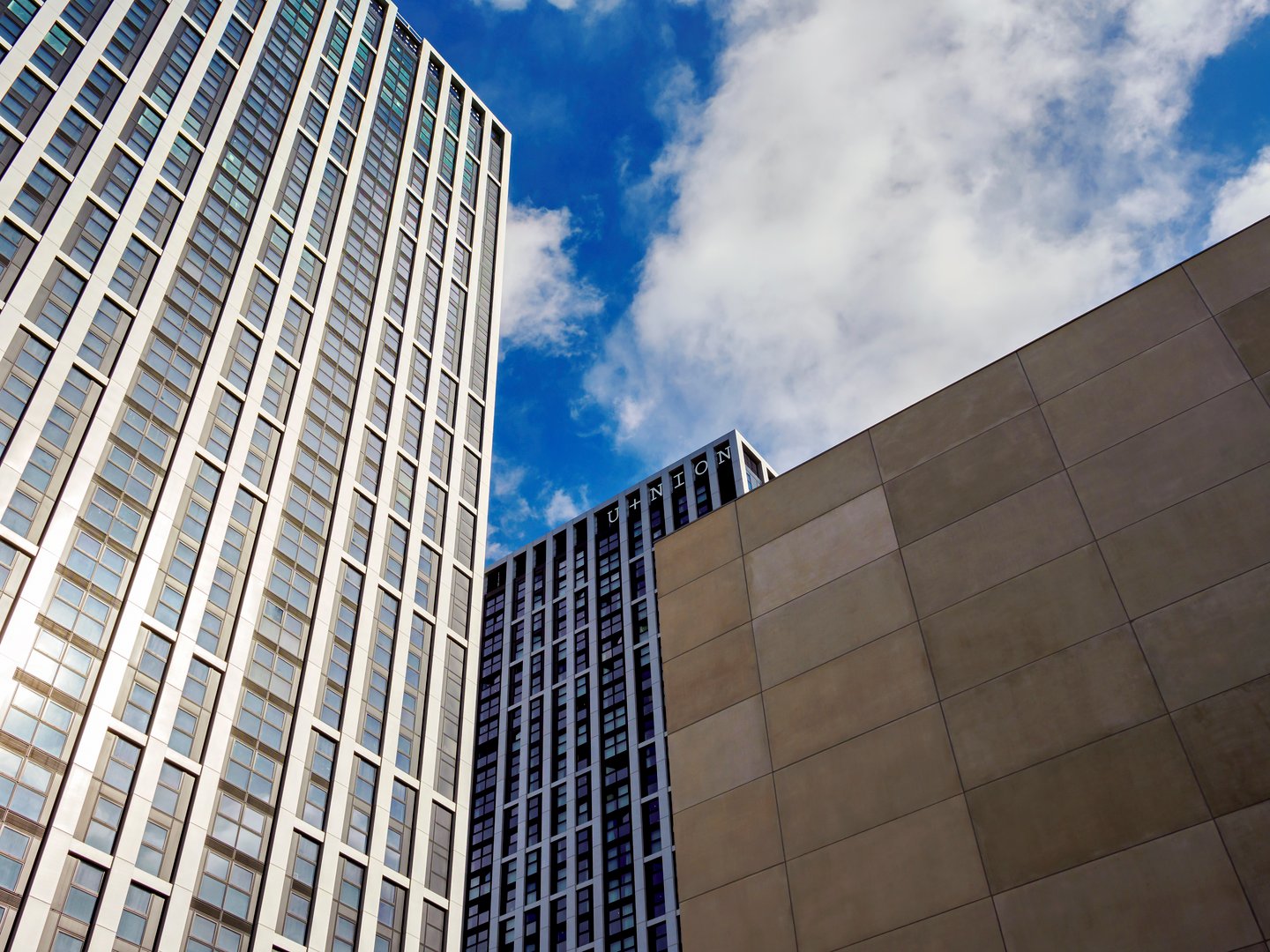 Modern high-rise buildings against a vibrant blue sky with clouds.