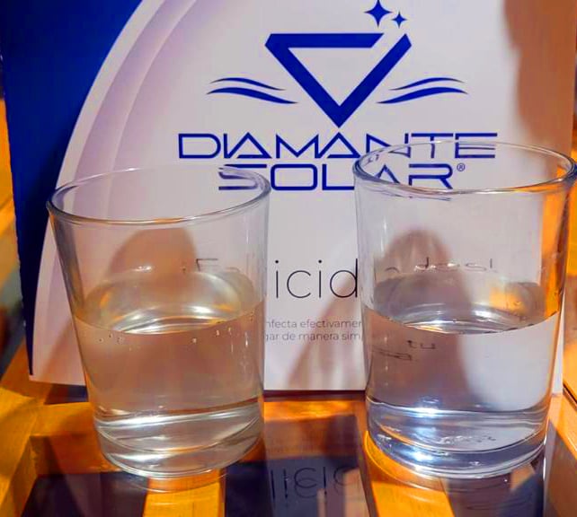 Two glasses of water in front of a box labeled "Diamante Solar" on a wooden surface.