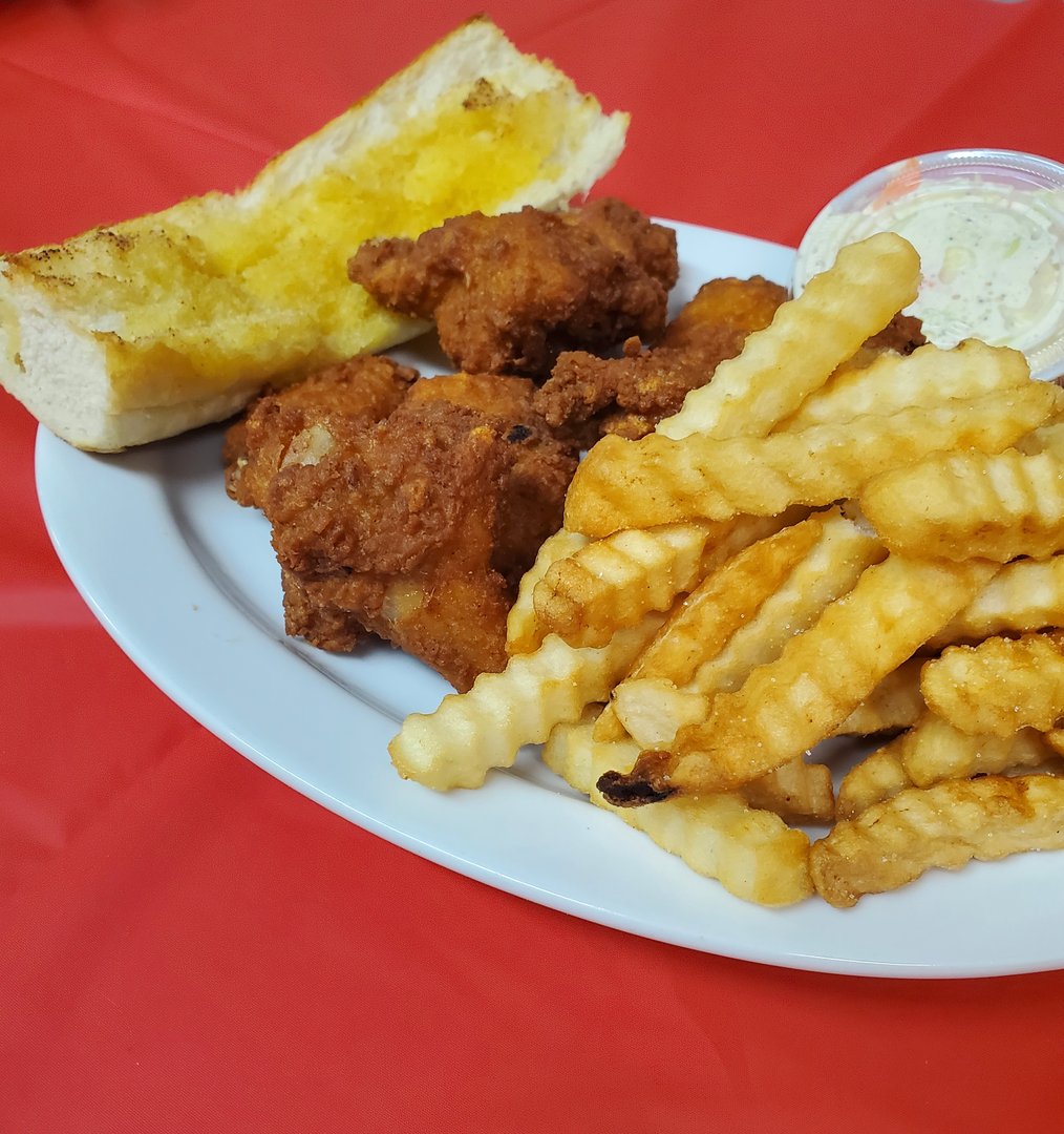 Plate of fried chicken, crinkle-cut fries, garlic bread, and a side of coleslaw on a red tablecloth.