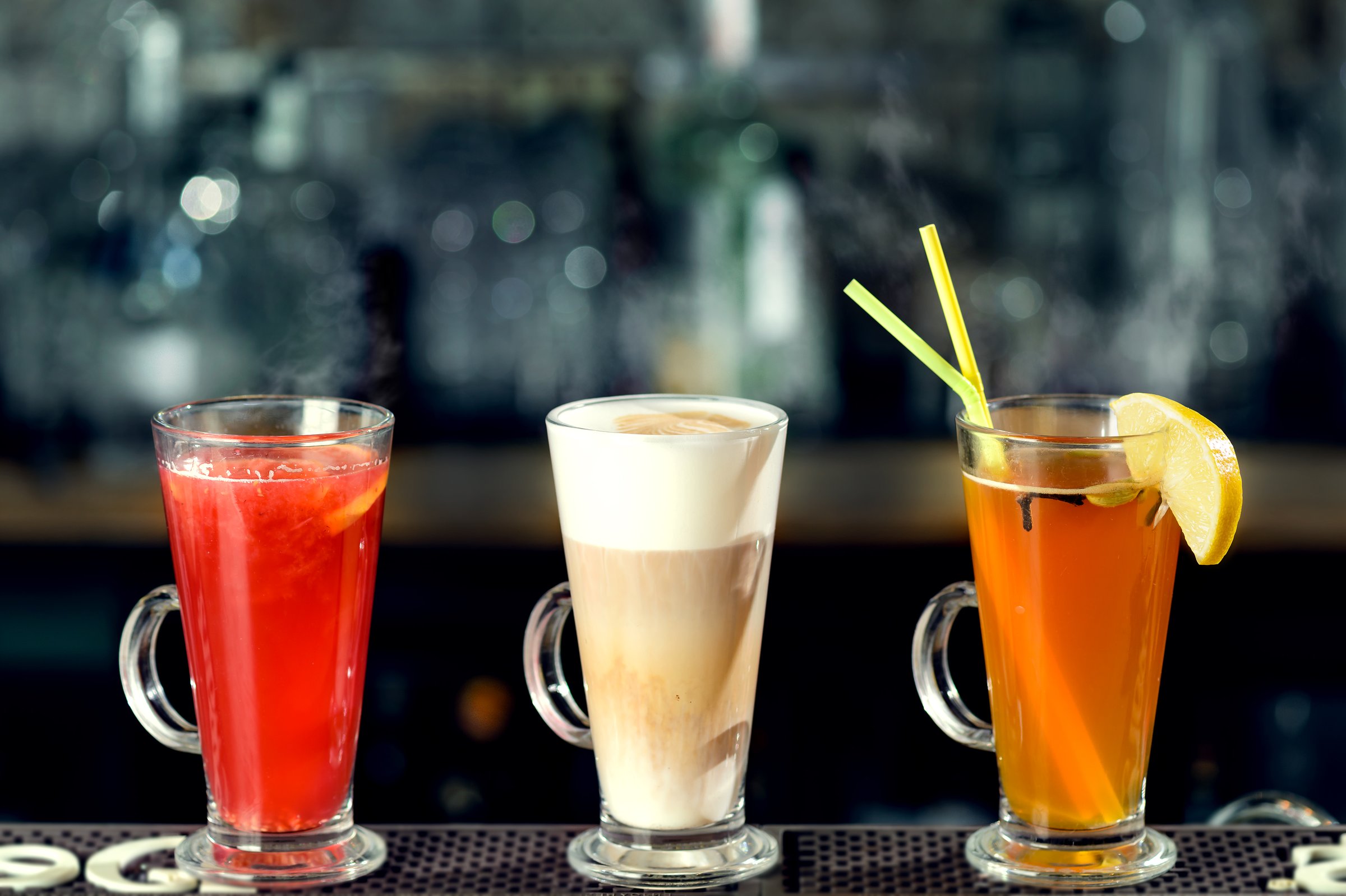Latte and hot alcoholic cocktails with steam at the bar counter