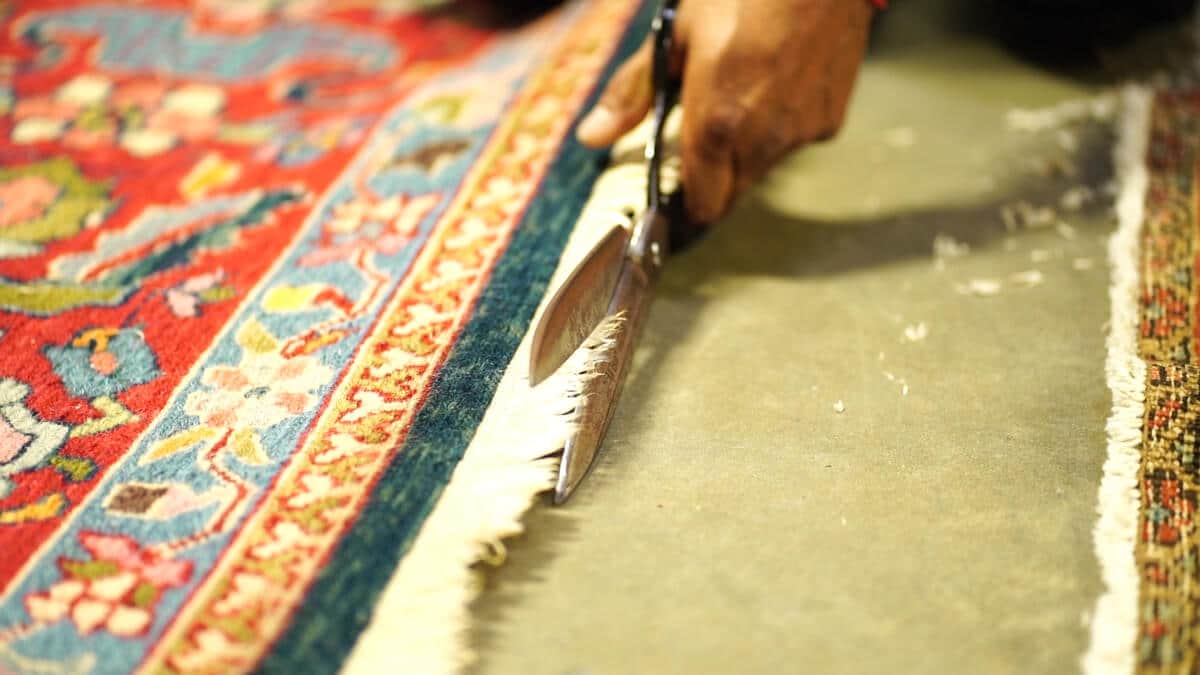 Skilled artisan performing detailed antique rug repair - close-up of hand weaving and restoration techniques