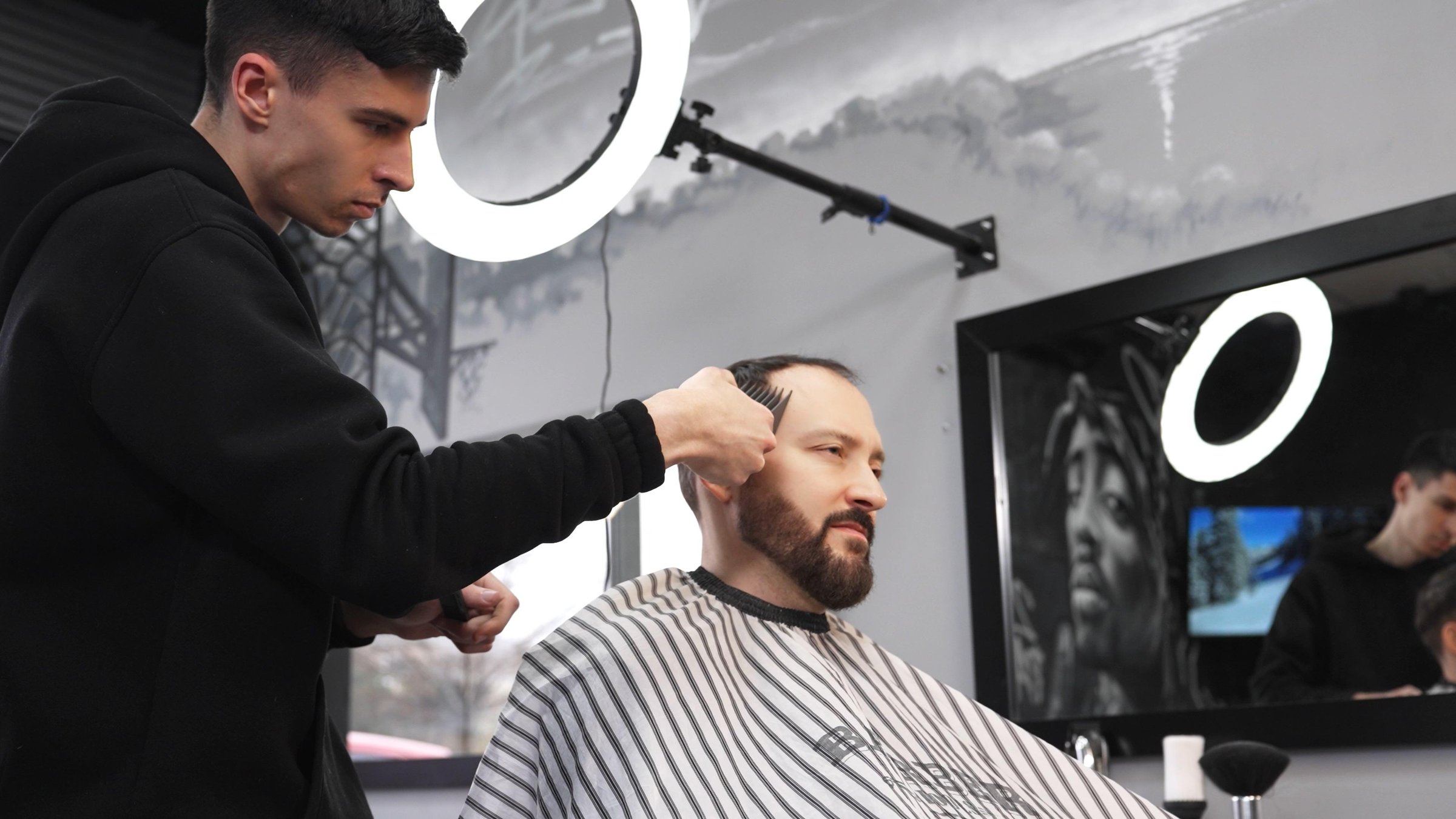 Professional barber carefully trimming male client's hair with electric clippers, delivering precise grooming inside contemporary barbershop with modern styling techniques