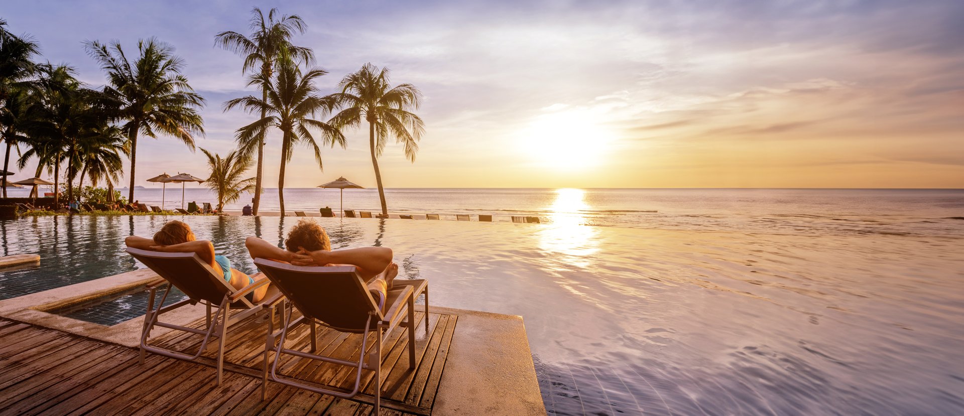 beach holidays for couple in luxury hotel, banner background with copyspace, man and woman relaxing near swimming pool at sunset