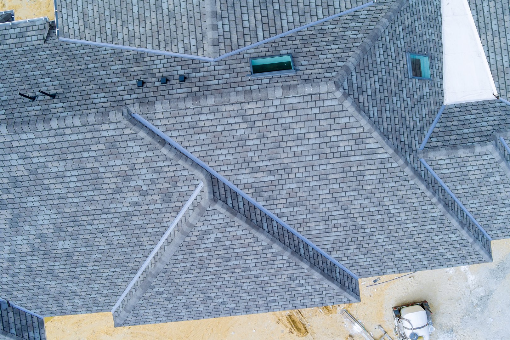 Overhead view of newly built house with gray slate roof, exposed construction materials in works day