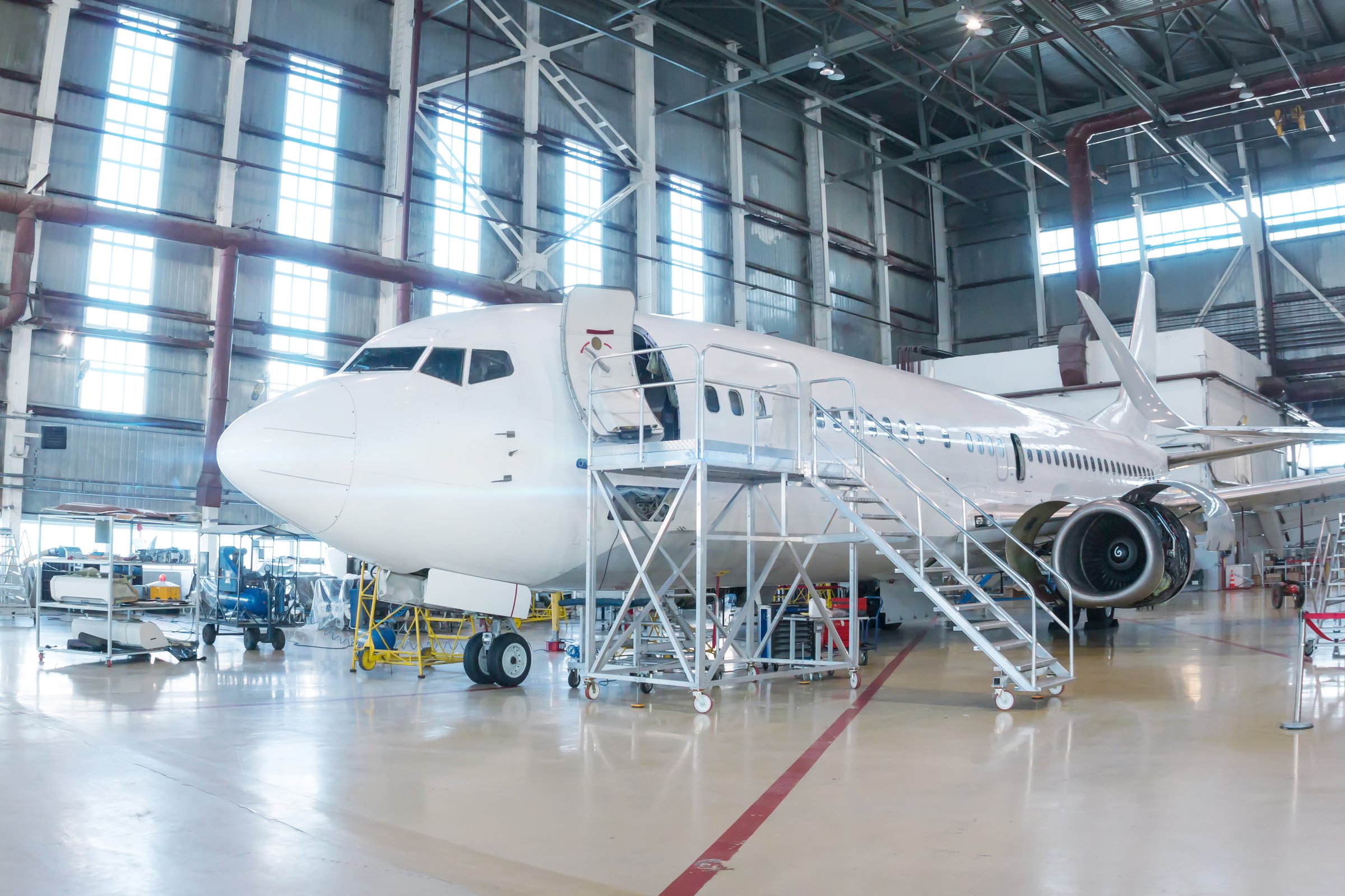 White passenger airplane in the hangar. Airliner under maintenance. Checking mechanical systems for flight operations