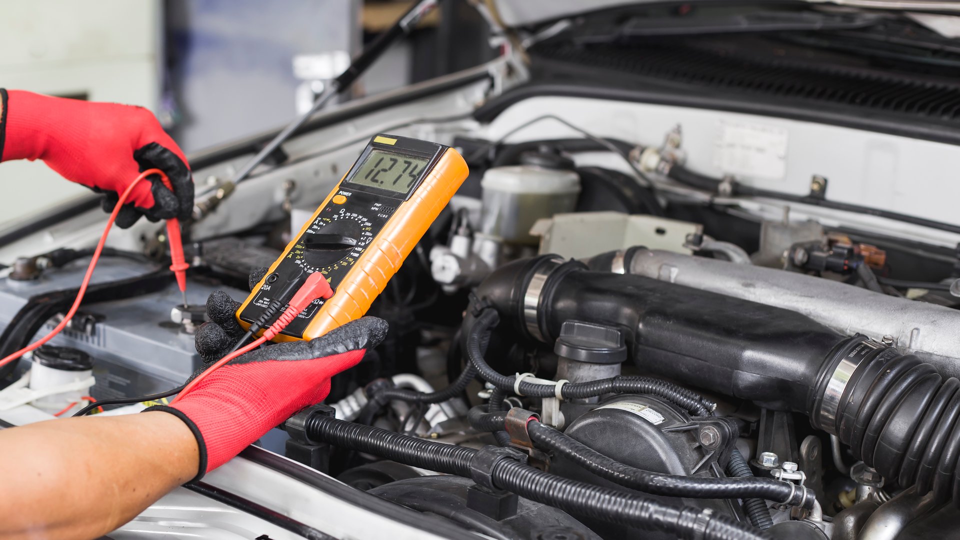 A technician is checking the car battery for availability.