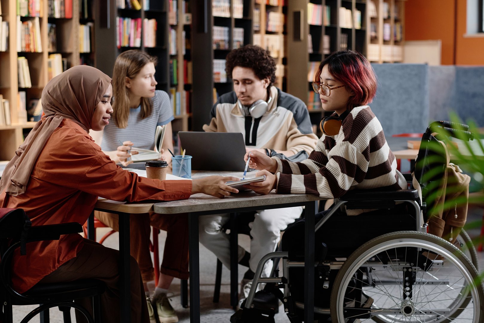 Group of diverse male and female students spending time together studying in library