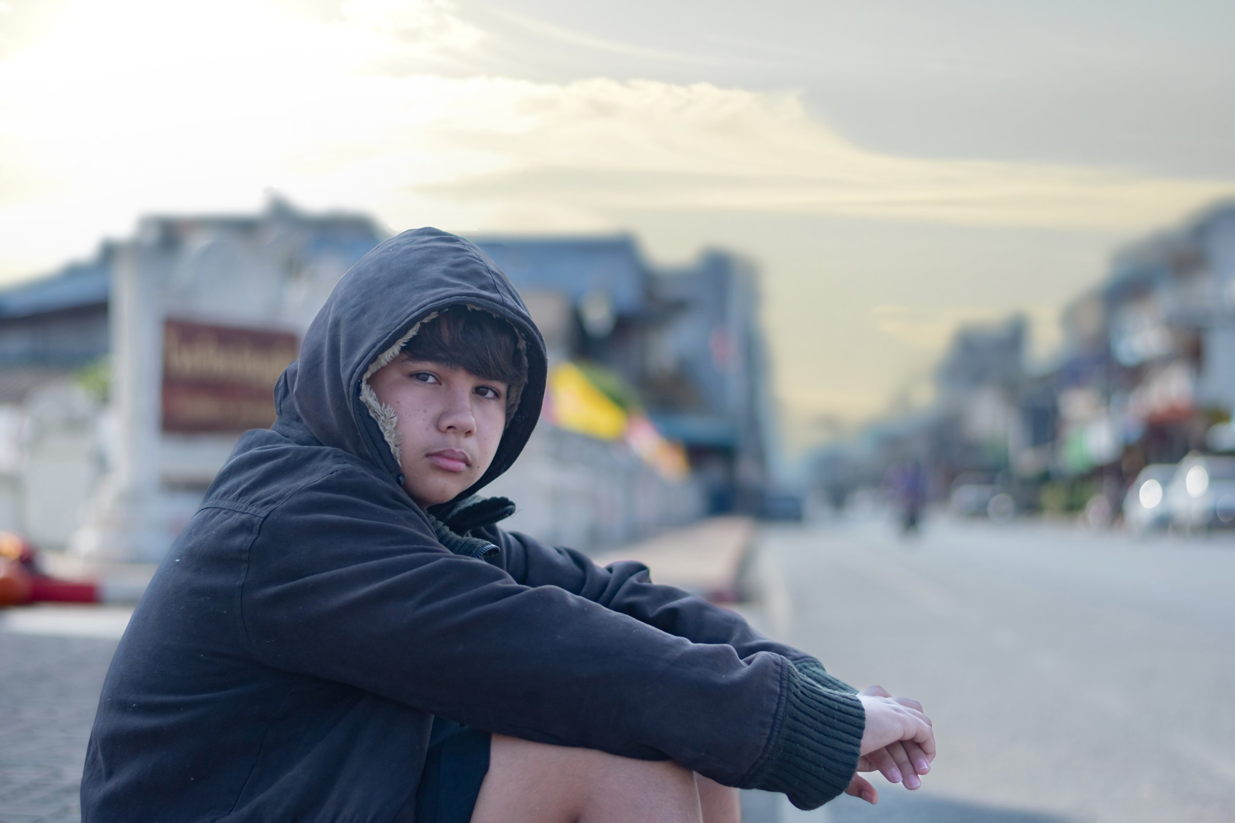 Portrait of young asian boy who has broken family, homeless, living, sleeping and sitting beside rural road, sunlight edited, concept for social problems of young people around the world.