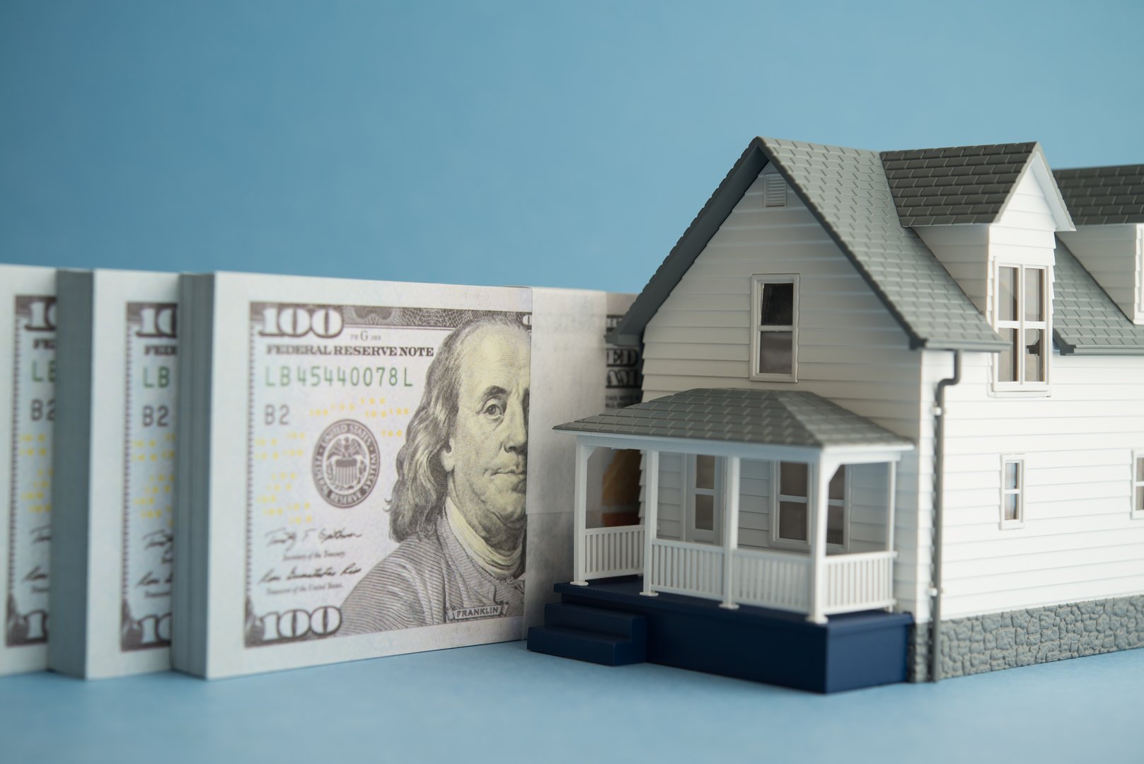 House and US dollar banknotes on blue background. Financial planning for home buying, mortgage loan, home equity loan, home for cash, banking, real estate property and so on concept.