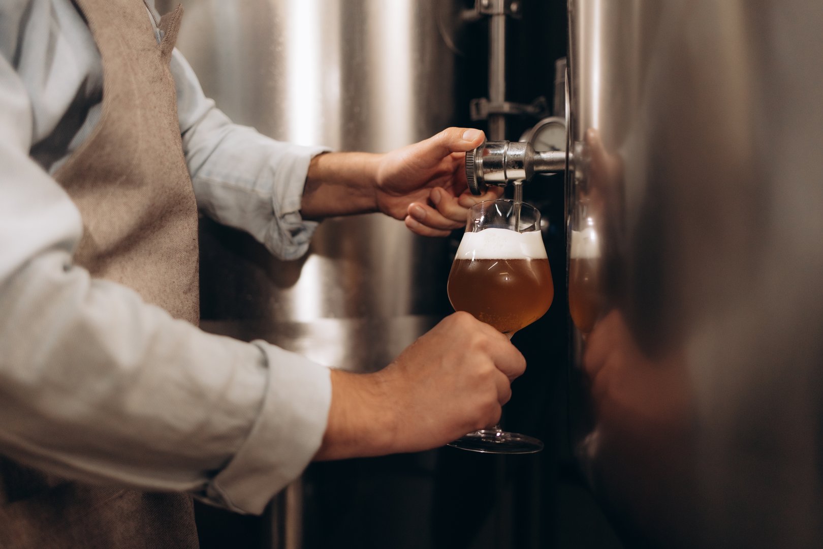 Brewery master tasting beer in production facility. Small family business, production of craft beer.